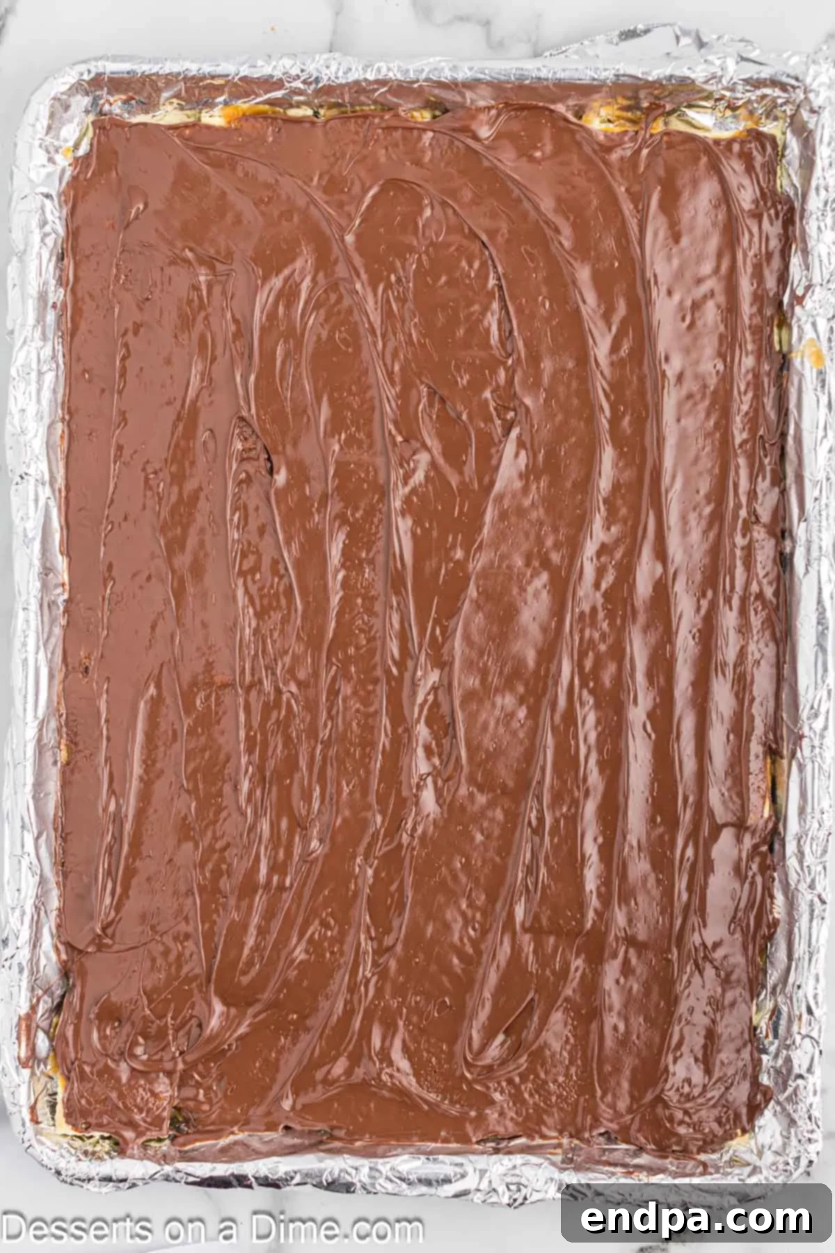 A smooth, even layer of melted chocolate covering the Christmas Crack, topped with a colorful assortment of festive sprinkles for a cheerful holiday look.