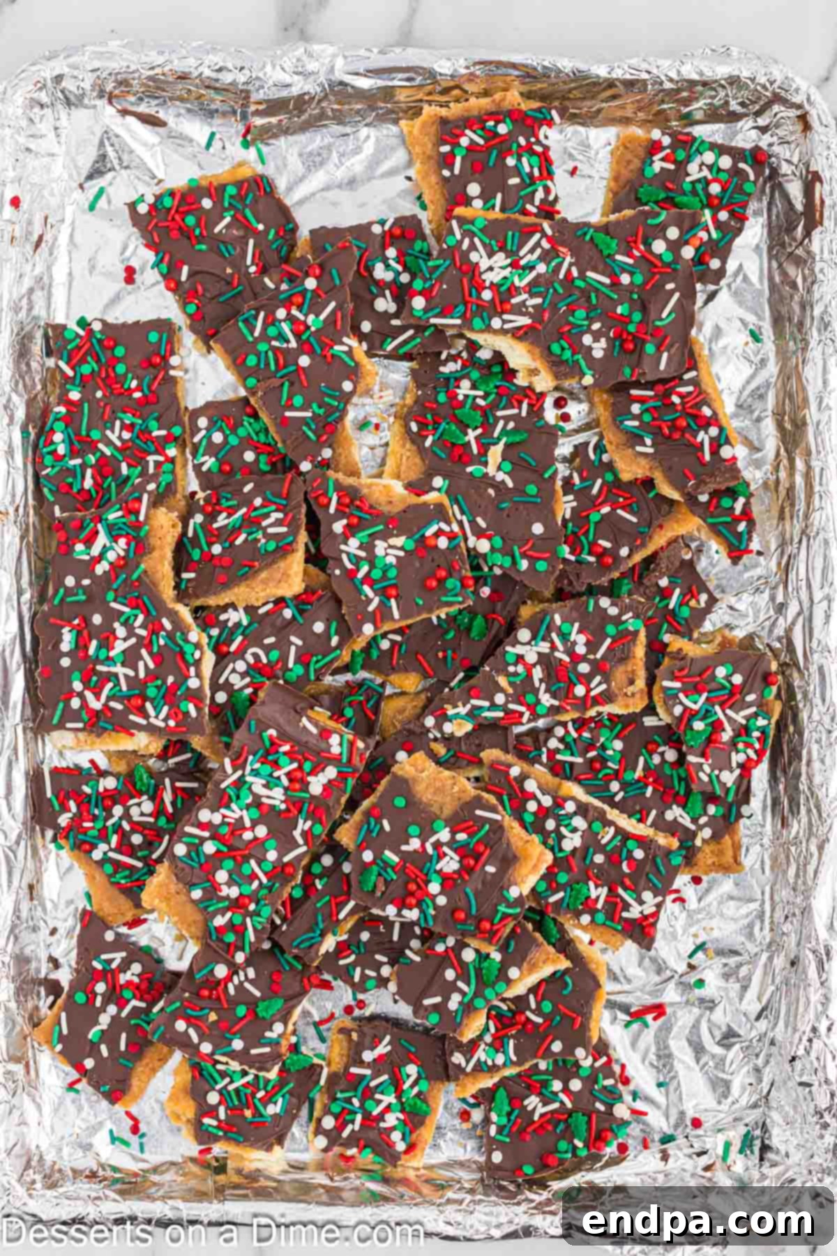Hardened Christmas crack carefully broken into various bite-sized pieces, showcasing the distinct layers of cracker, toffee, and chocolate.