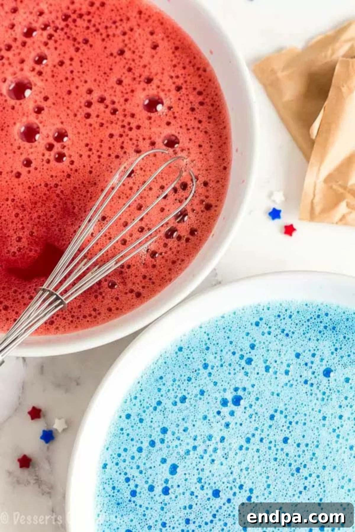 Close up image of red and blue Jell-O prepared in two separate bowls, ready to be poured over the cake.