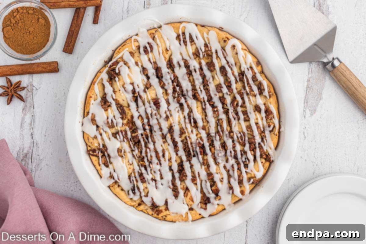 Homemade Cinnamon Roll Pie 2 A delicious Cinnamon Roll Pie topped with a generous drizzle of glaze, showcasing its golden crust and inviting texture.