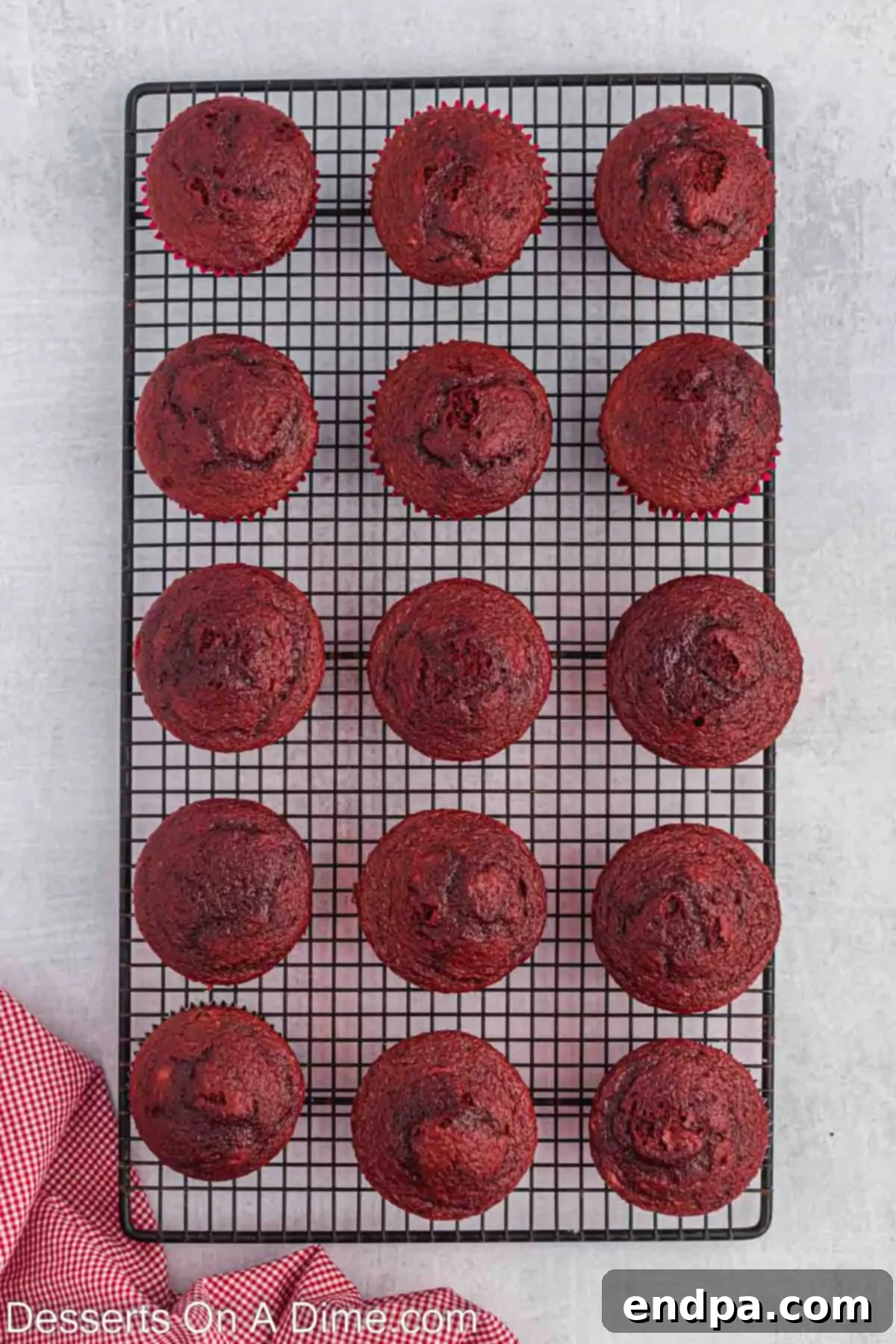 Freshly baked red velvet cupcakes carefully arranged on a wire rack, allowing them to cool completely before frosting.