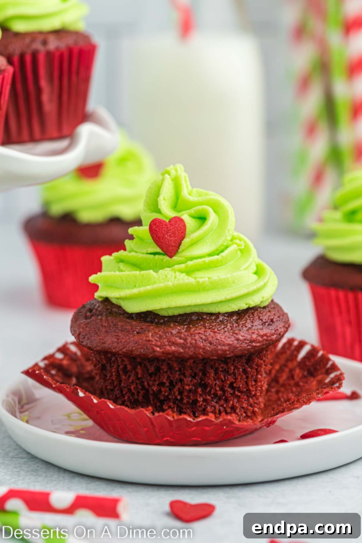 A collection of perfectly frosted Grinch cupcakes, with bright green swirls and red heart sprinkles, arranged artfully for a holiday display.