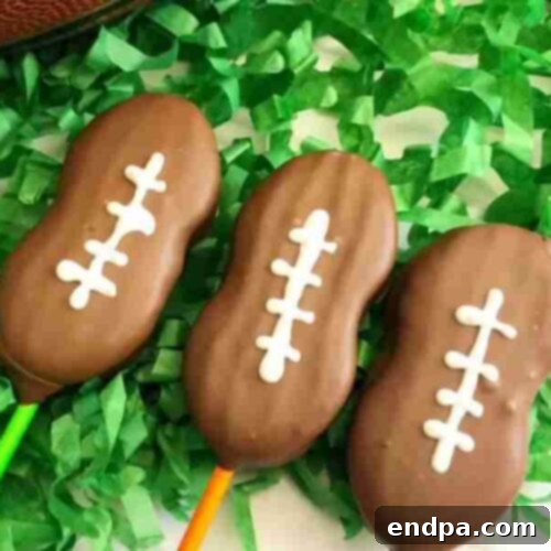 Touchdown Desserts: 55 Recipes for Your Super Bowl Party 4 Easy Football Cookie Pops decorated with white icing laces on sticks.