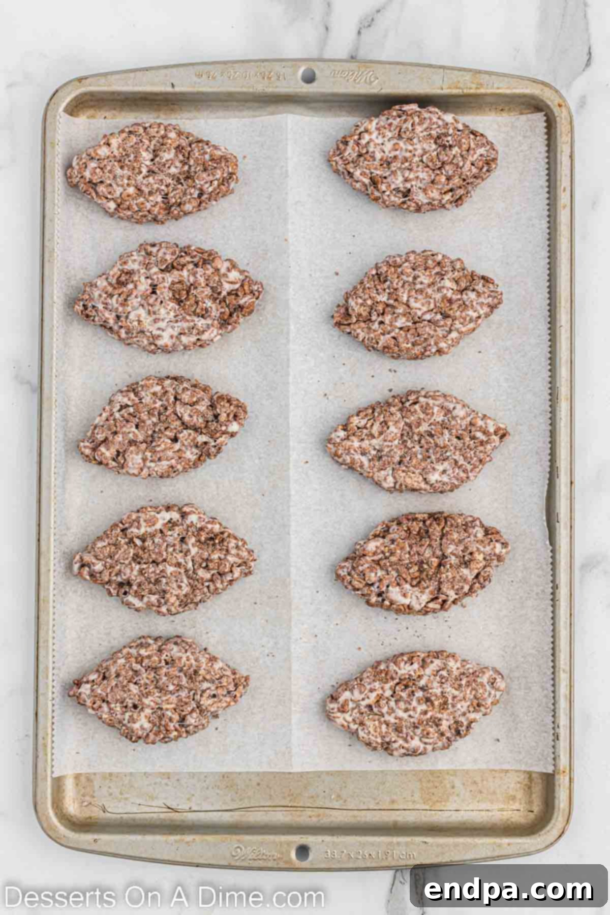 The Rice Krispie treat mixture being shaped by hand into distinct football forms.