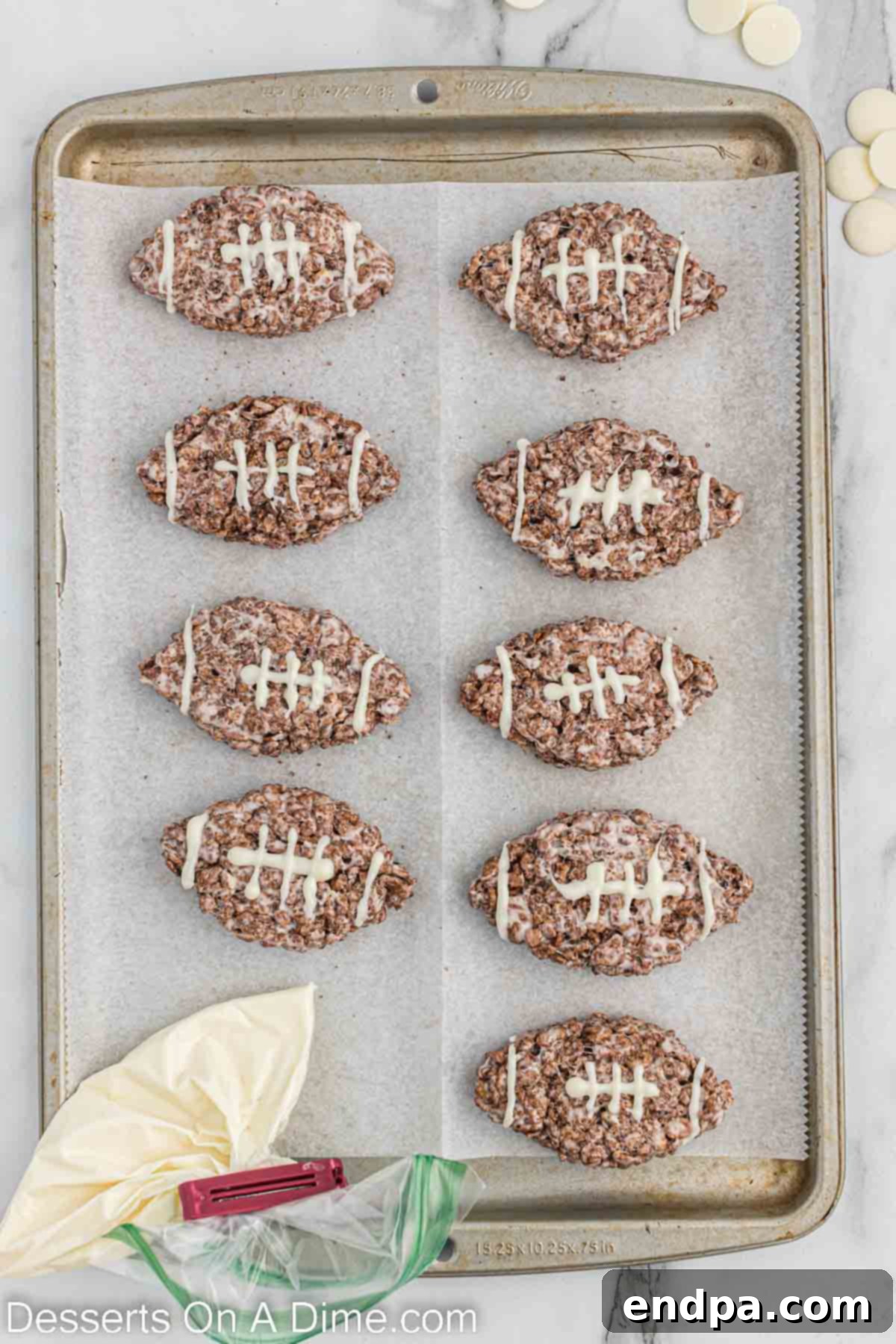 White chocolate being drizzled onto the football-shaped Rice Krispie treats to create decorative laces.