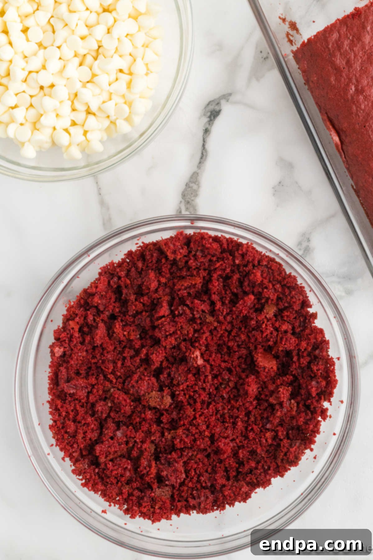 A bowl filled with finely crumbled red velvet cake, ready for mixing.