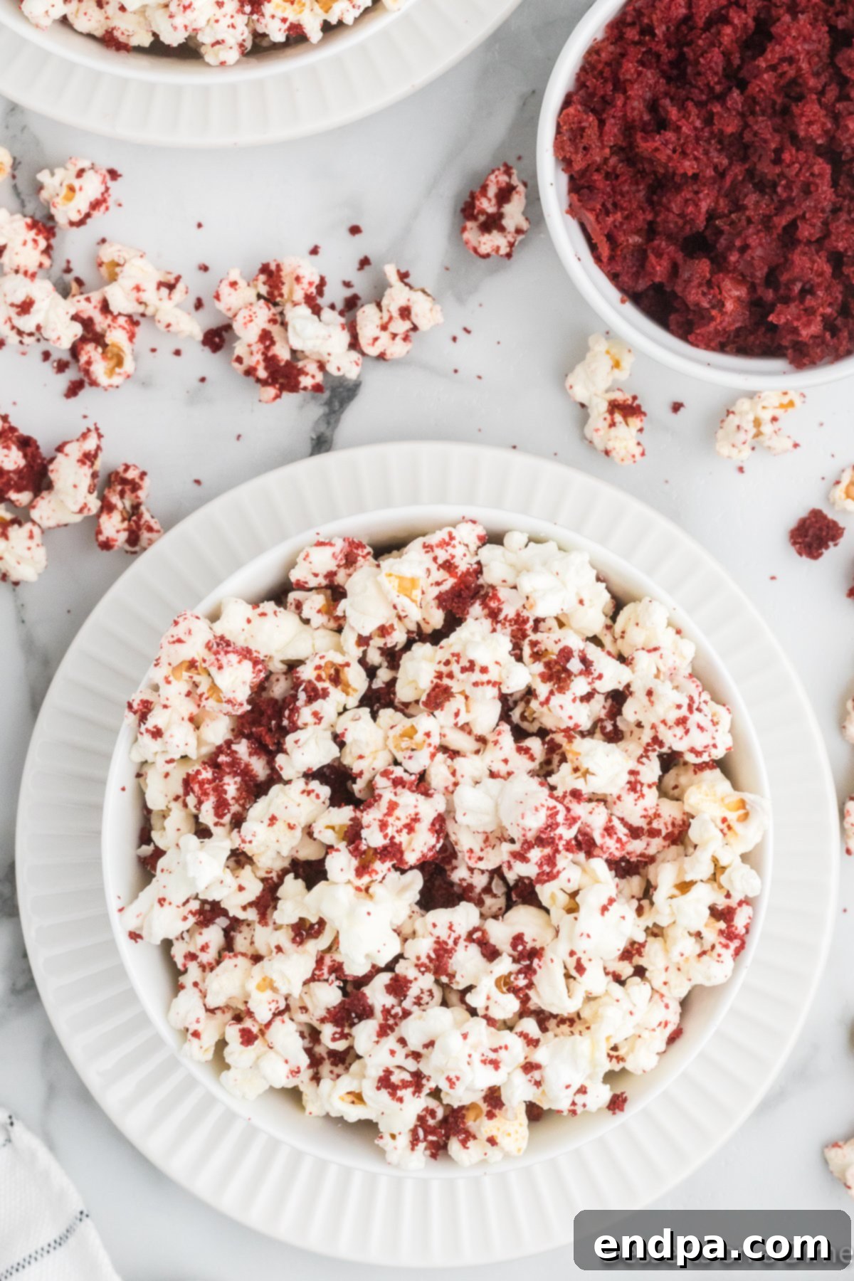 A beautifully arranged bowl of Red Velvet Popcorn, highlighting the vibrant red crumbs and white chocolate coating, ready for serving.