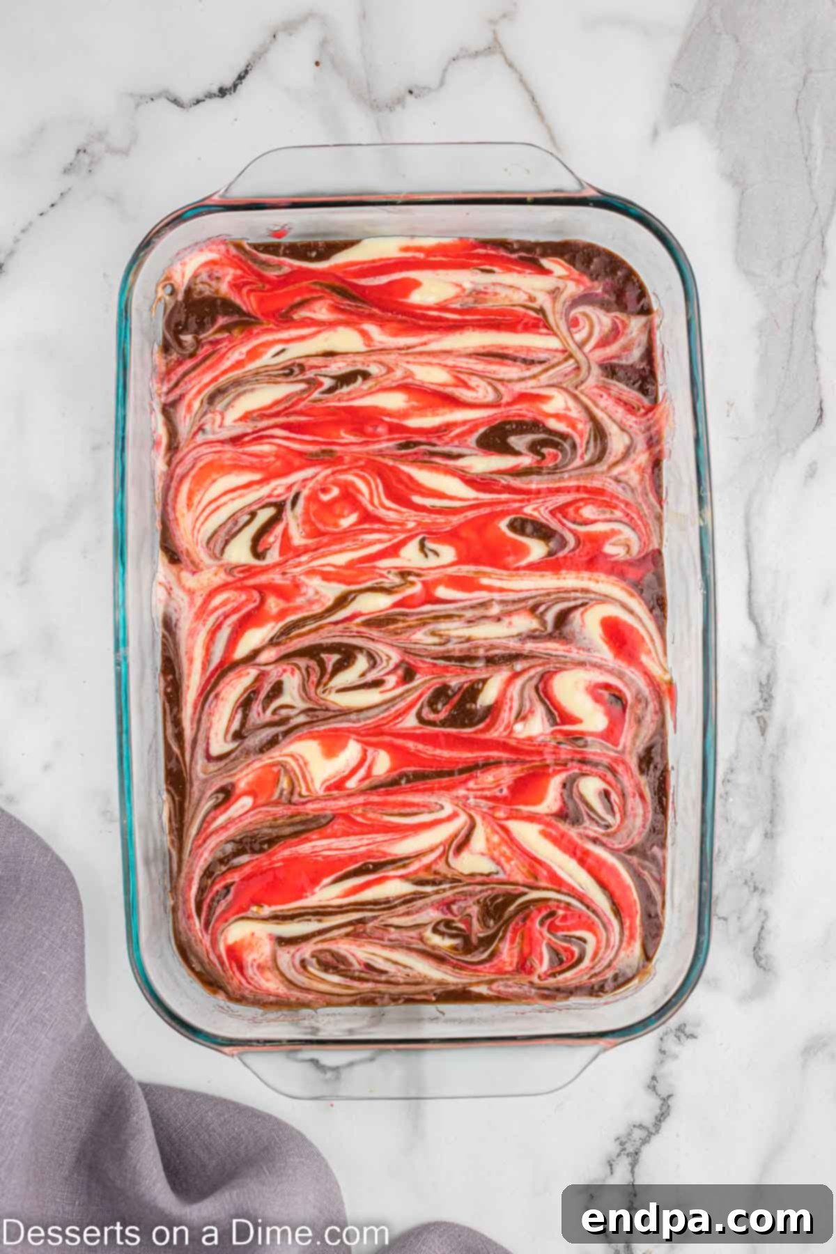 Swirling the cheesecake layer and raspberry layer into the brownie batter