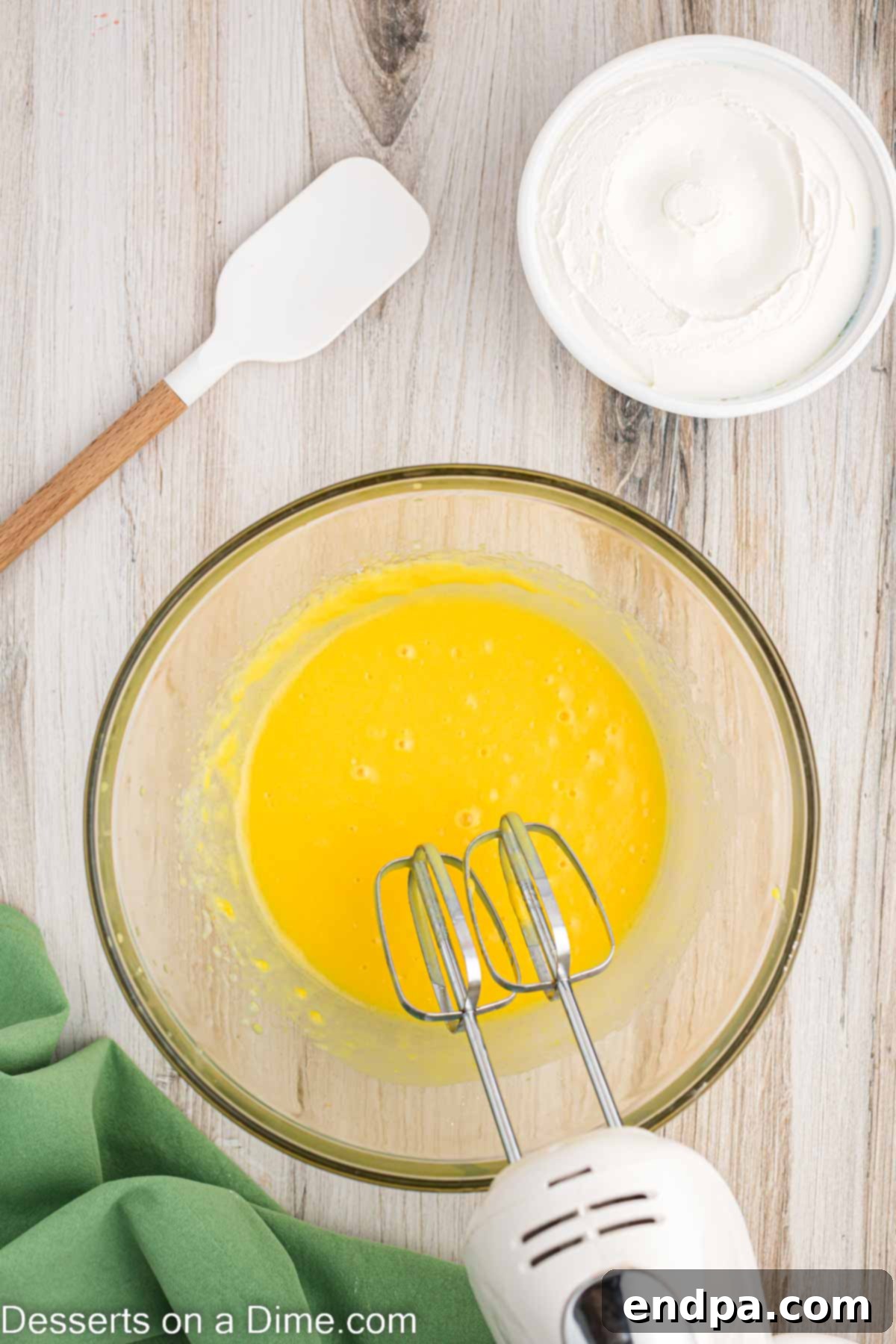 Super Fluffy Cool Whip Frosting 3 Pudding mixture being combined in a bowl with a hand mixer.