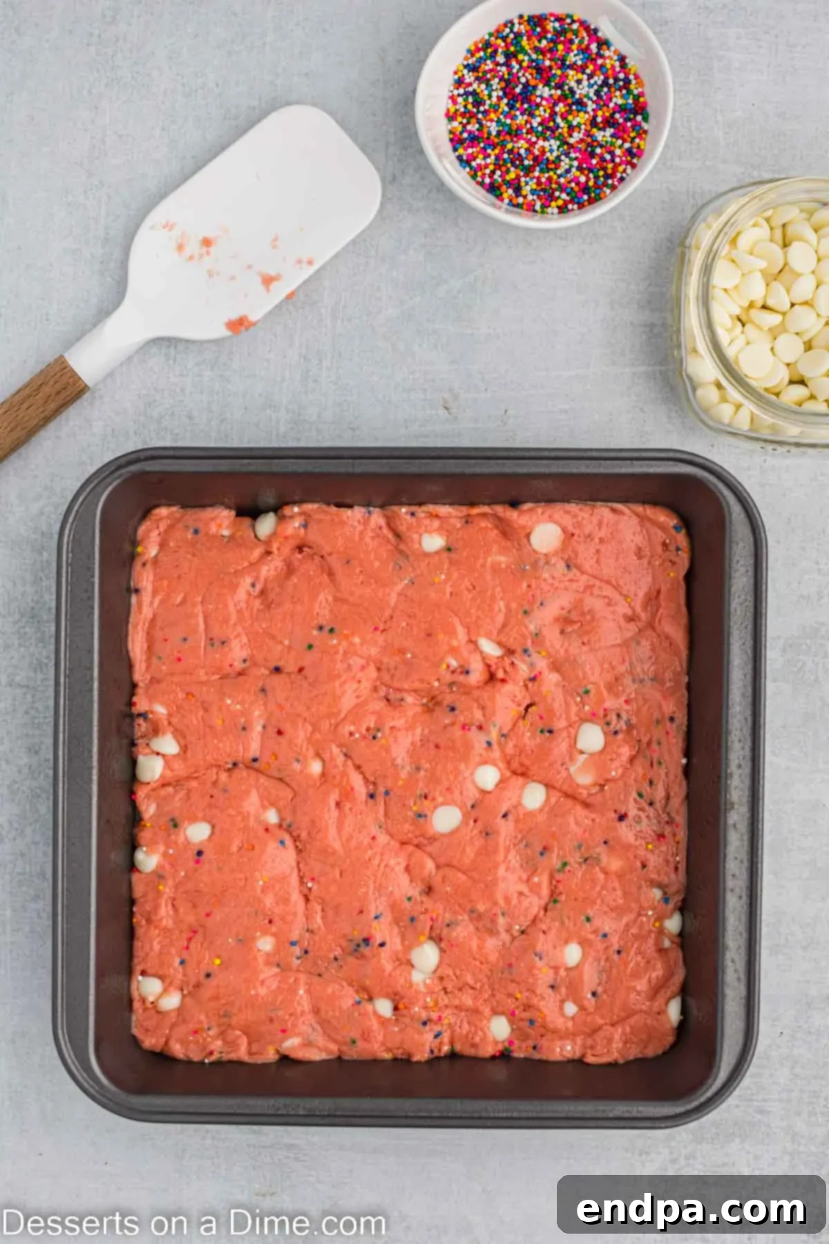 Spreading the thick strawberry brownie batter evenly into the prepared baking pan.