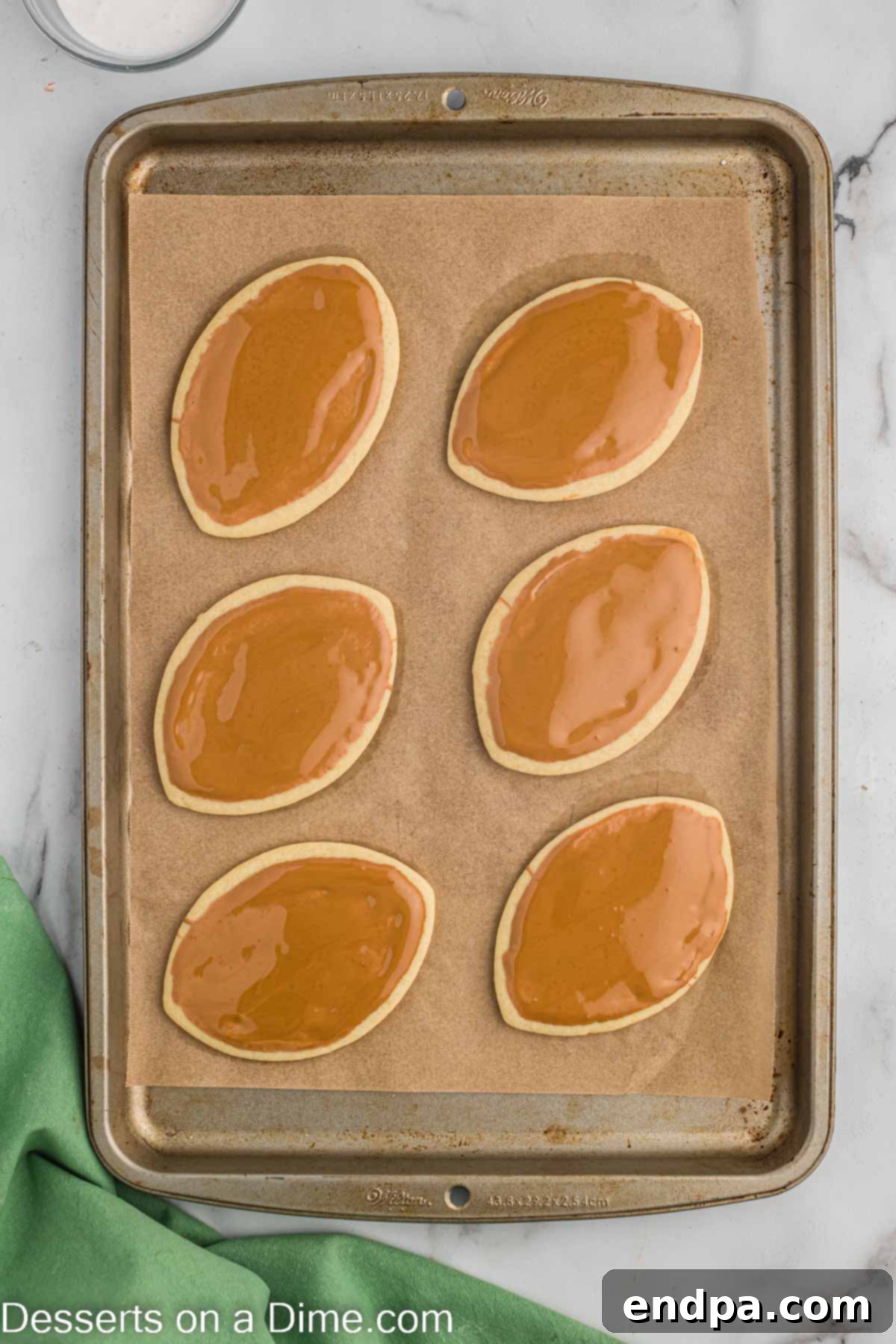 Touchdown Sugar Cookies 13 Football sugar cookies with a smooth, dark brown royal icing base, now cooling to set the color.