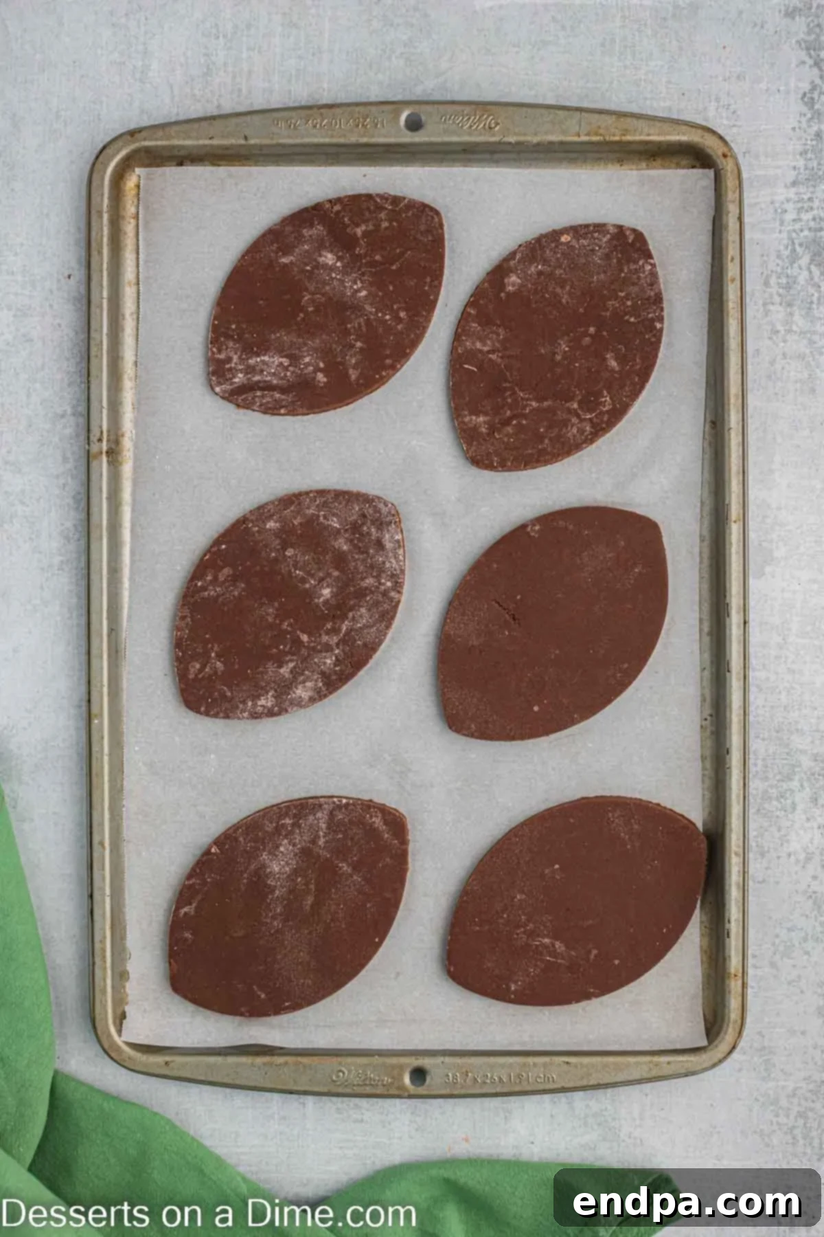 Championship Chocolate Football Cookies 8 Football-shaped cookies neatly arranged on a parchment-lined baking sheet, ready for the oven.