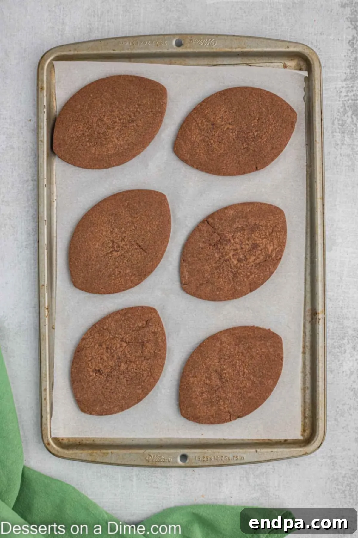 Championship Chocolate Football Cookies 9 Freshly baked chocolate football cookies on a baking sheet, with slightly firm edges.