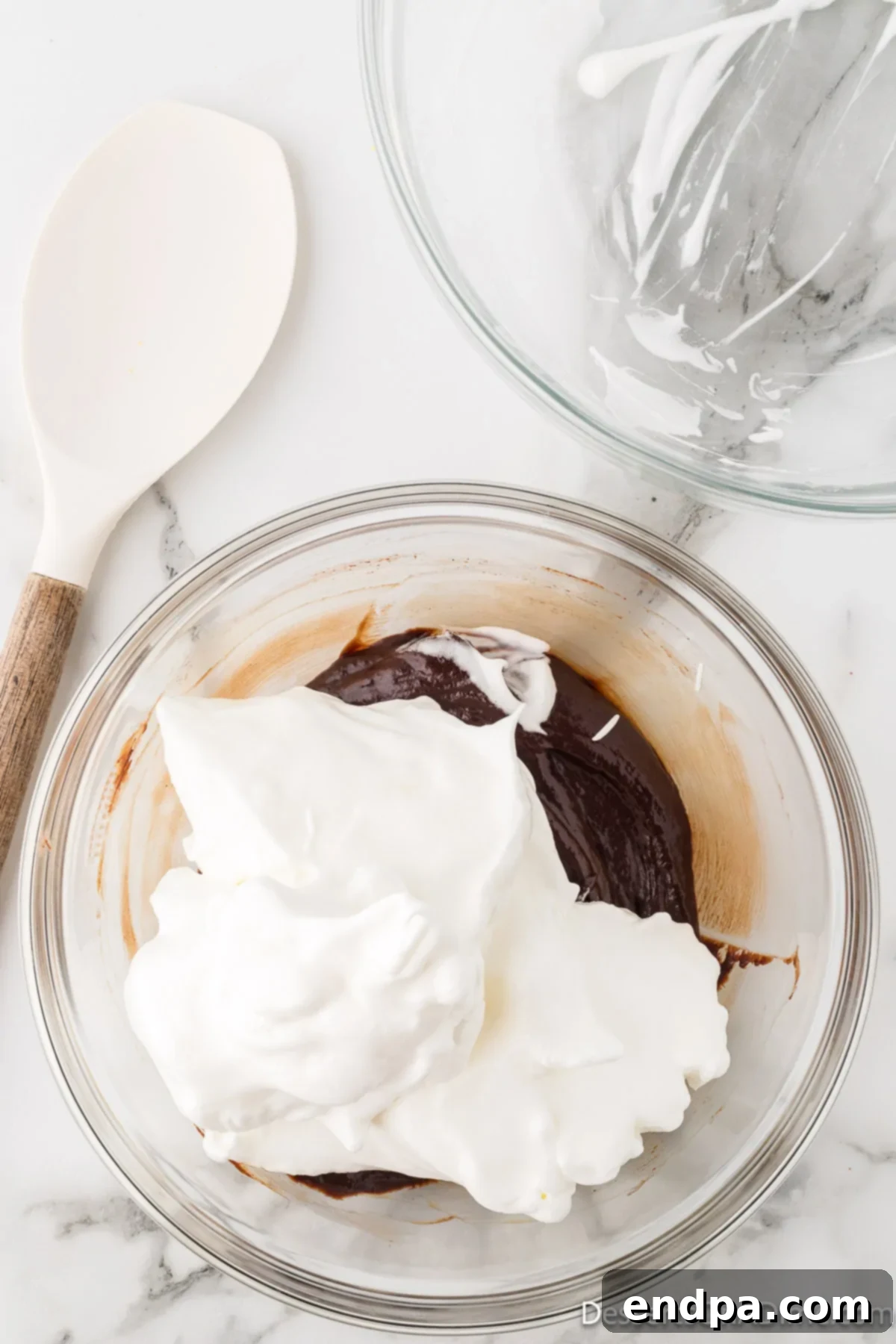 Velvety Chocolate Bliss 12 The airy, stiffly beaten egg white mixture being gently folded into the rich chocolate and egg yolk base with a spatula.