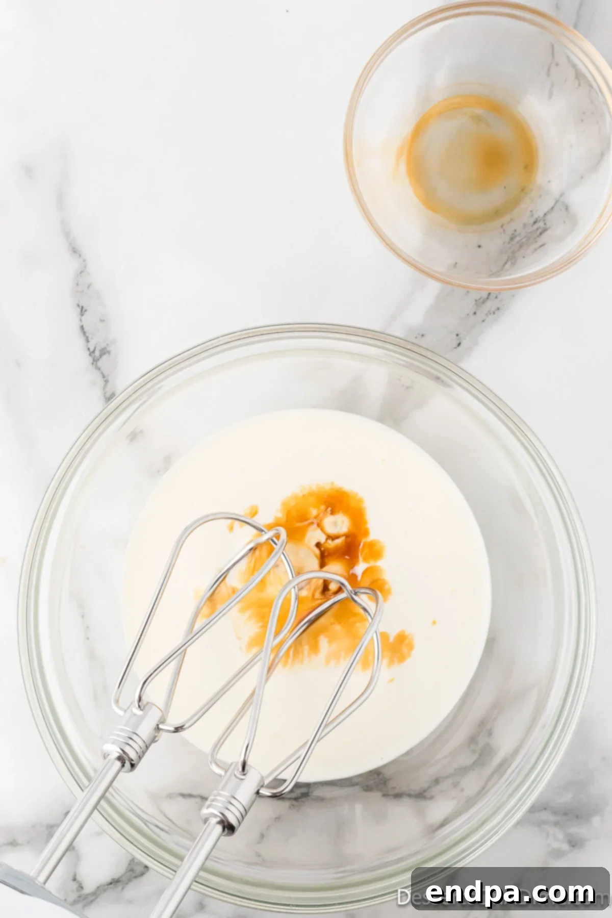 Velvety Chocolate Bliss 14 Chilled heavy whipping cream and vanilla extract in a bowl, ready to be beaten to fluffy peaks for the mousse.