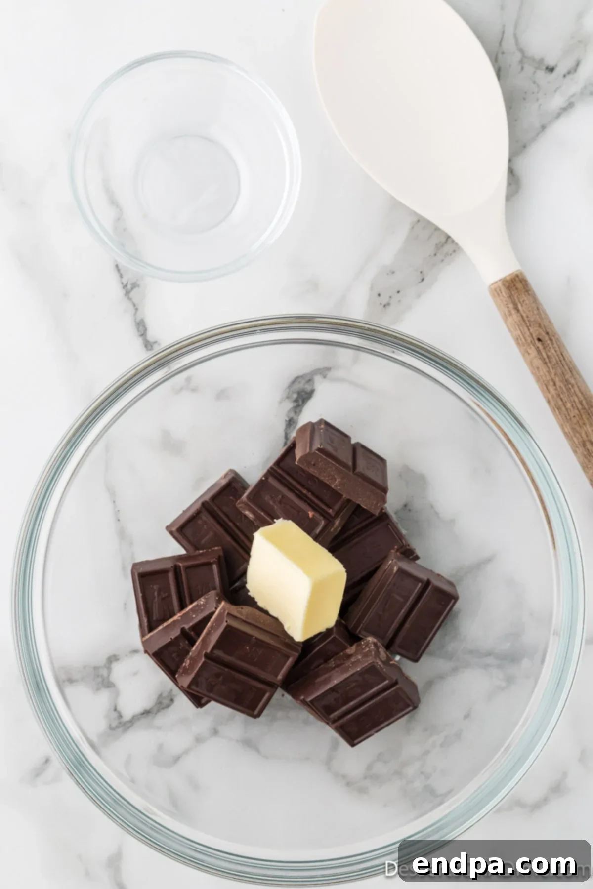 Velvety Chocolate Bliss 4 Pieces of high-quality semi-sweet chocolate and a dollop of unsalted butter in a microwave-safe mixing bowl.