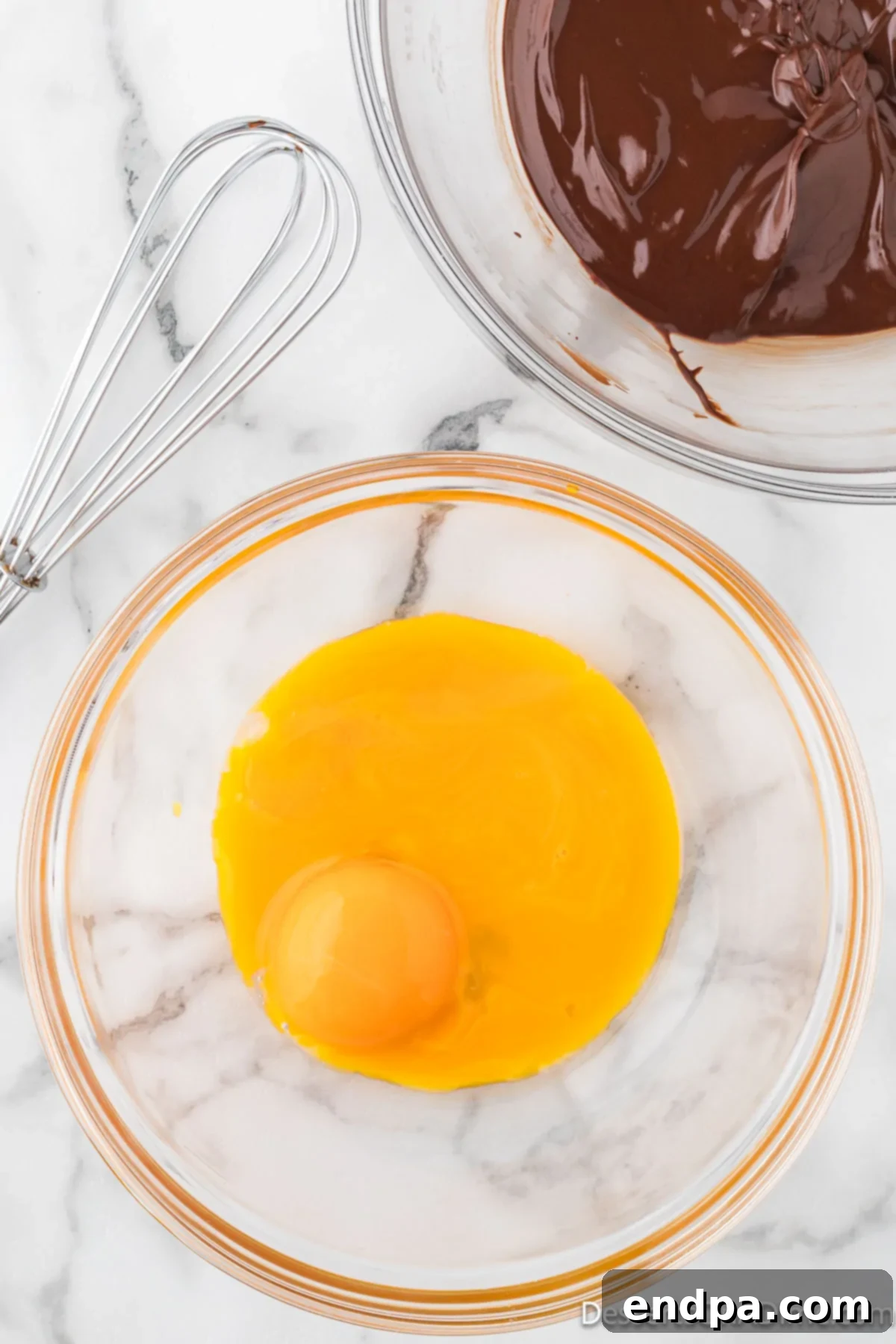 Velvety Chocolate Bliss 6 Three bright yellow egg yolks separated from their whites, resting in a pristine mixing bowl.