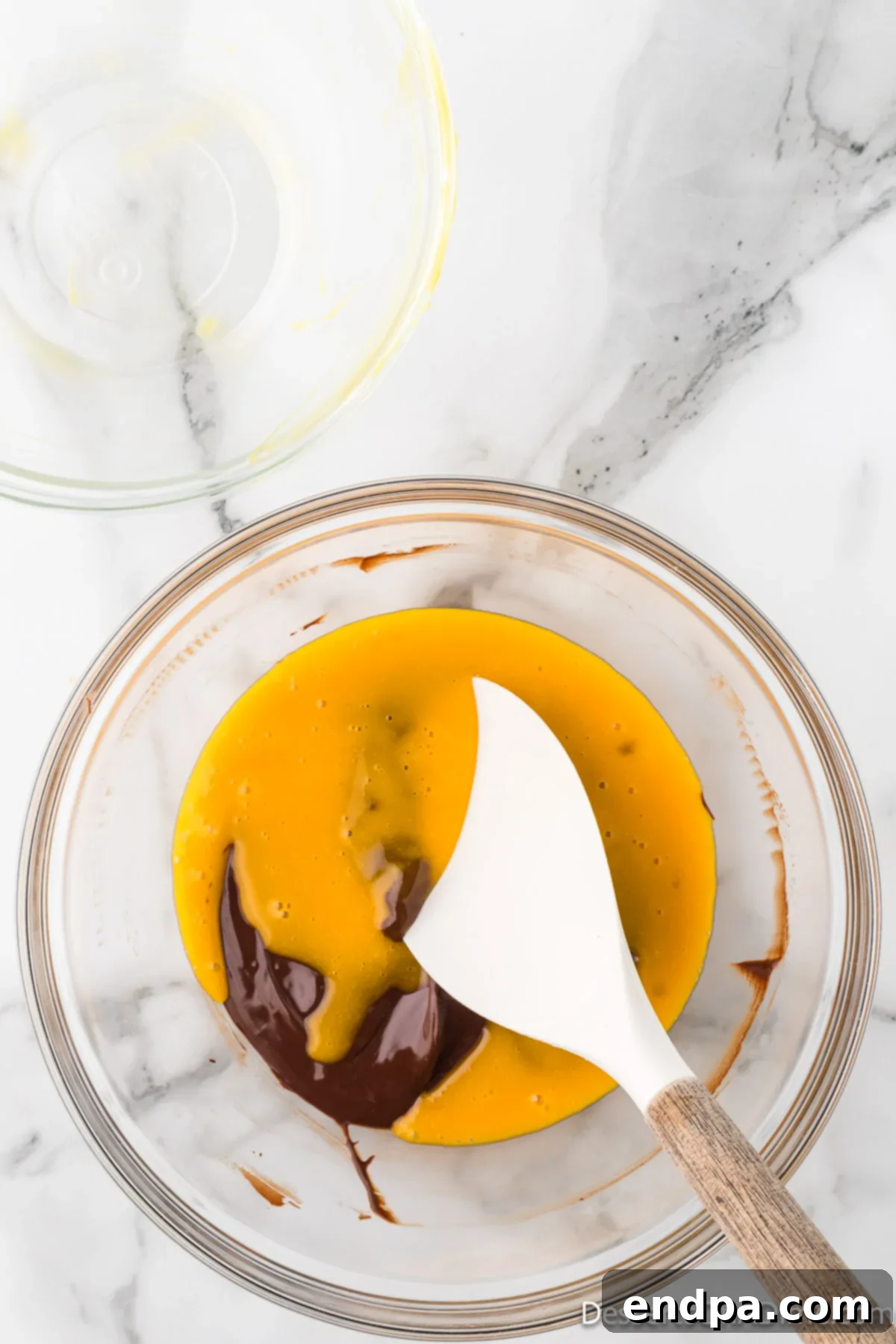 Velvety Chocolate Bliss 7 The rich, melted chocolate mixture and the whisked egg yolks are combined in a bowl, ready to be blended.