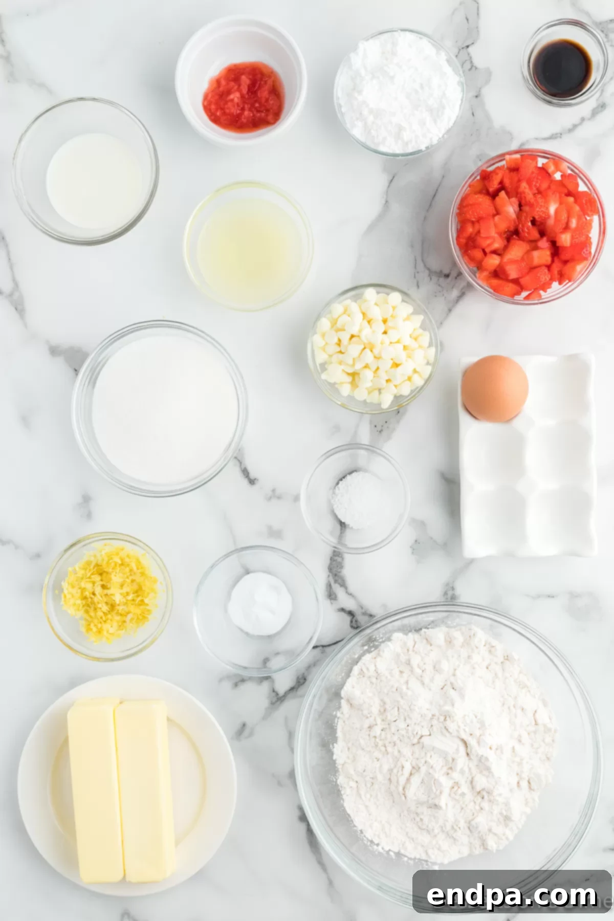 Various ingredients laid out for making Strawberry Lemon Blondies -butter, sugar, egg, lemon juice, flour, strawberries, white chocolate chips, powdered sugar, and milk.