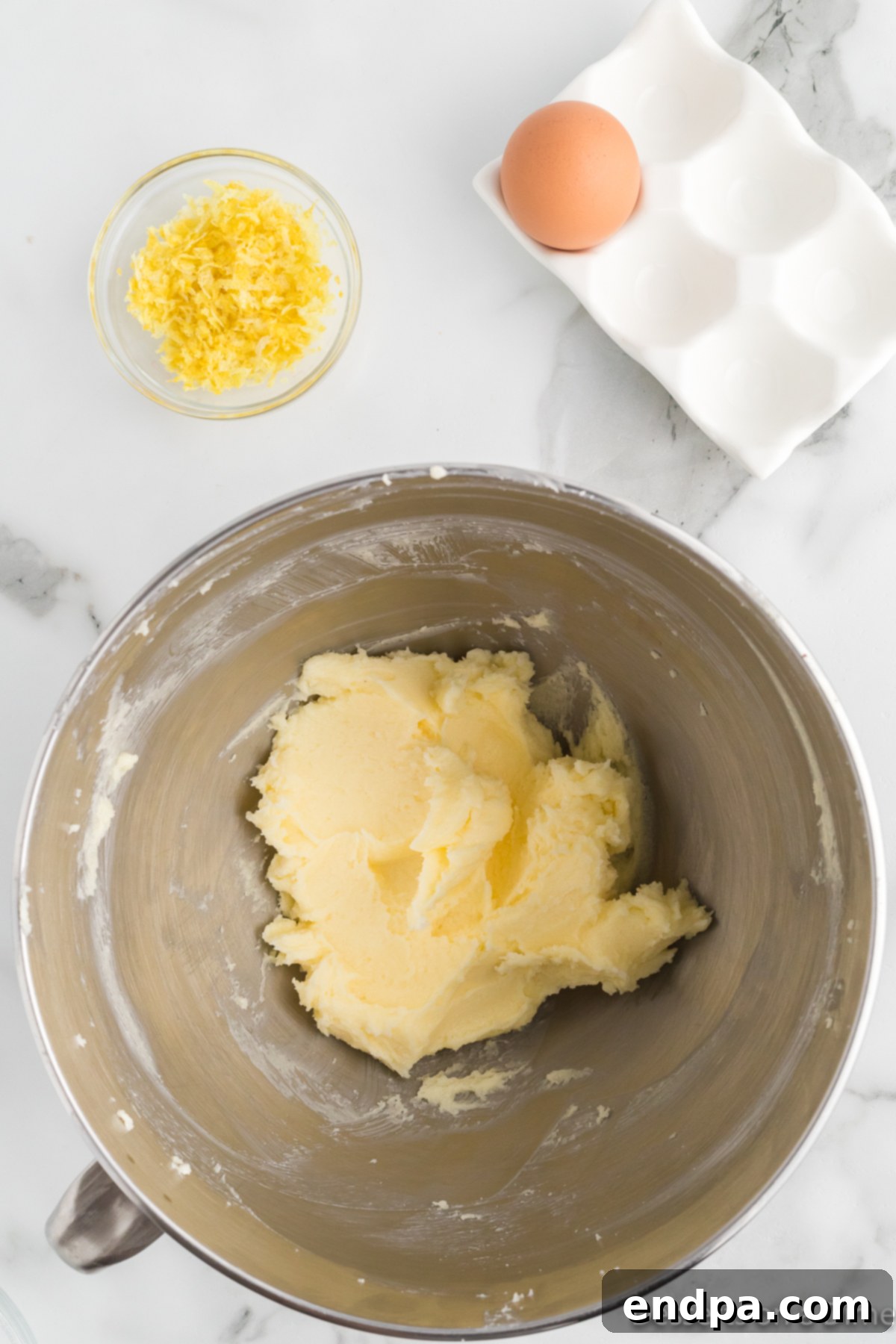 Stand mixer bowl with softened butter and granulated sugar being creamed until light and fluffy.