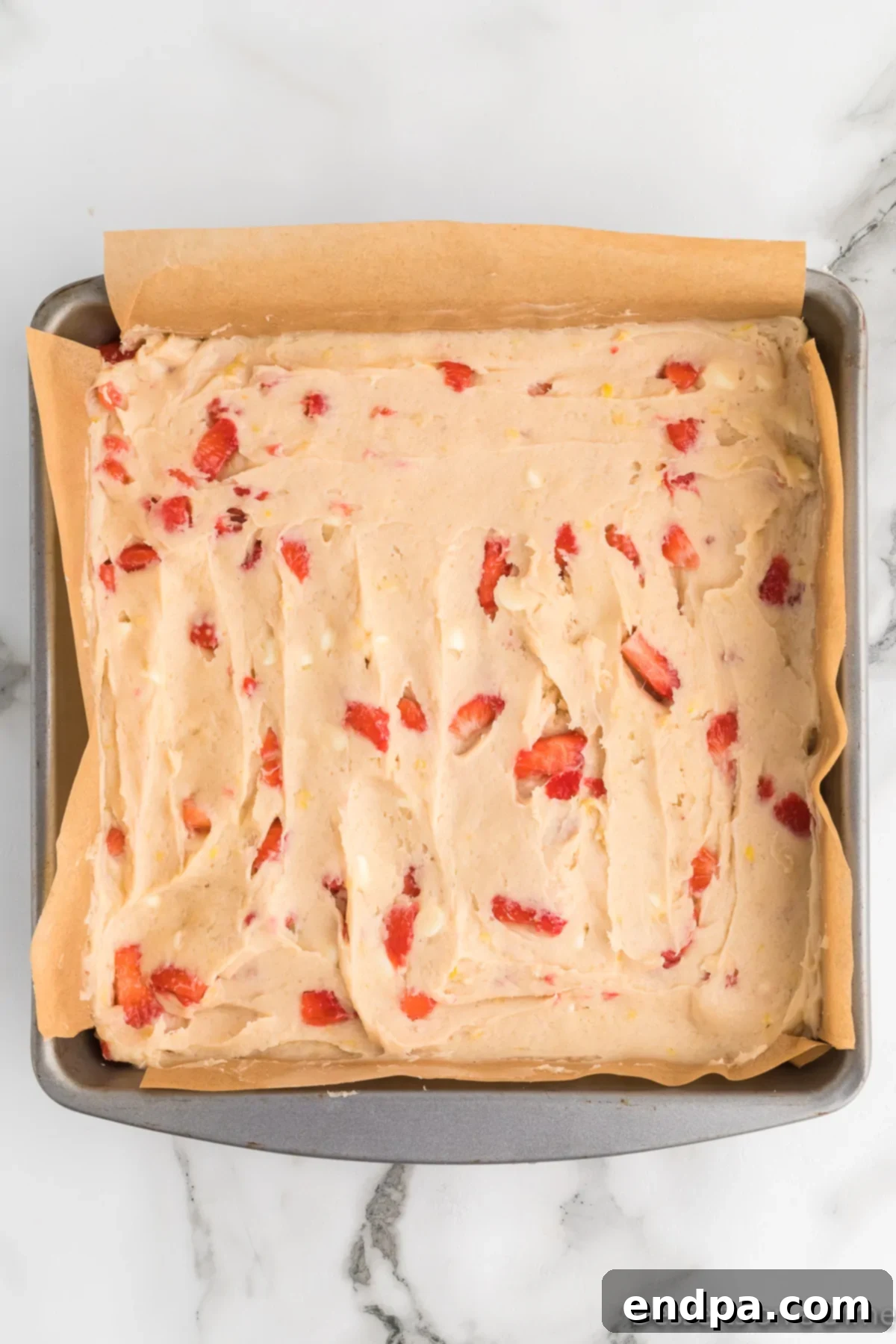 Blondie batter spread evenly into the parchment-lined baking pan.