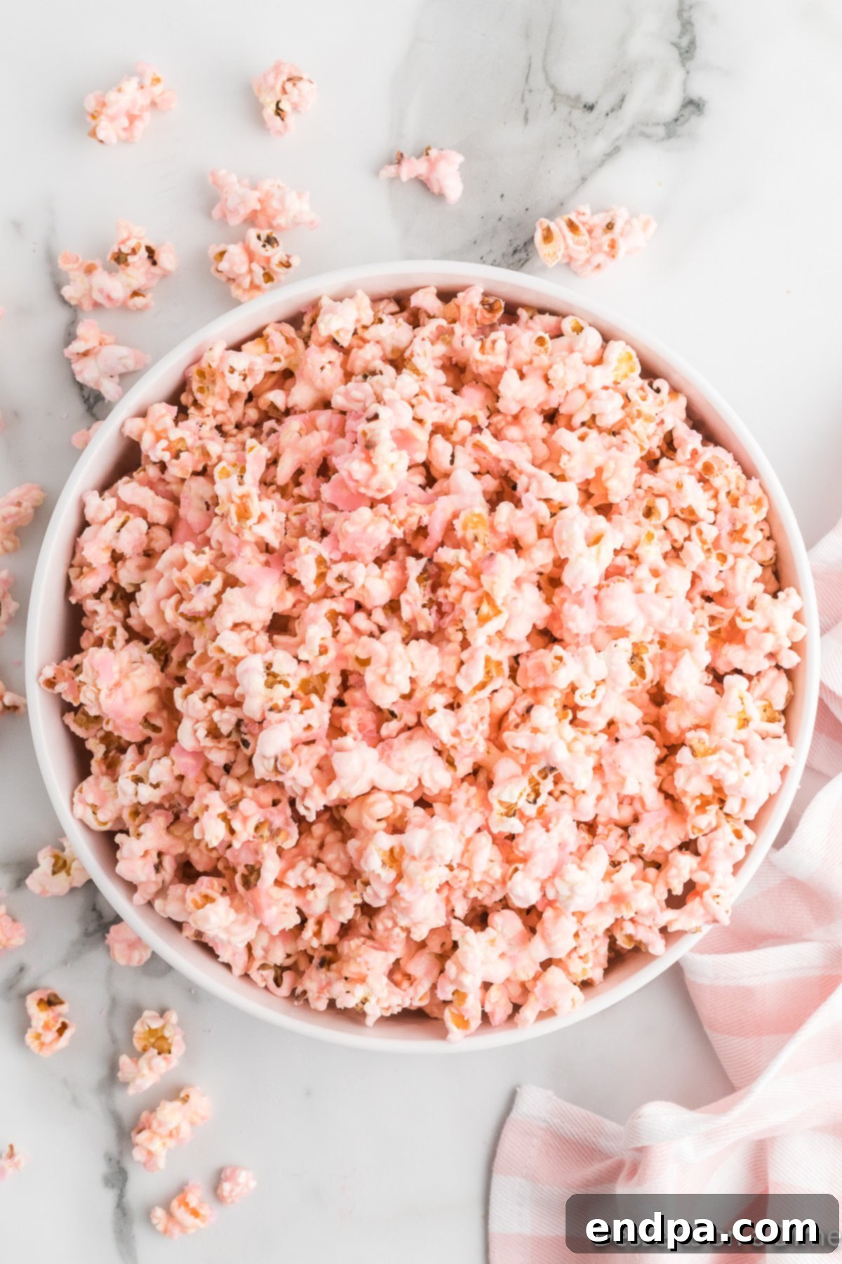 A close-up shot of perfectly coated, vibrant pink popcorn in a white bowl, showing its glossy texture.