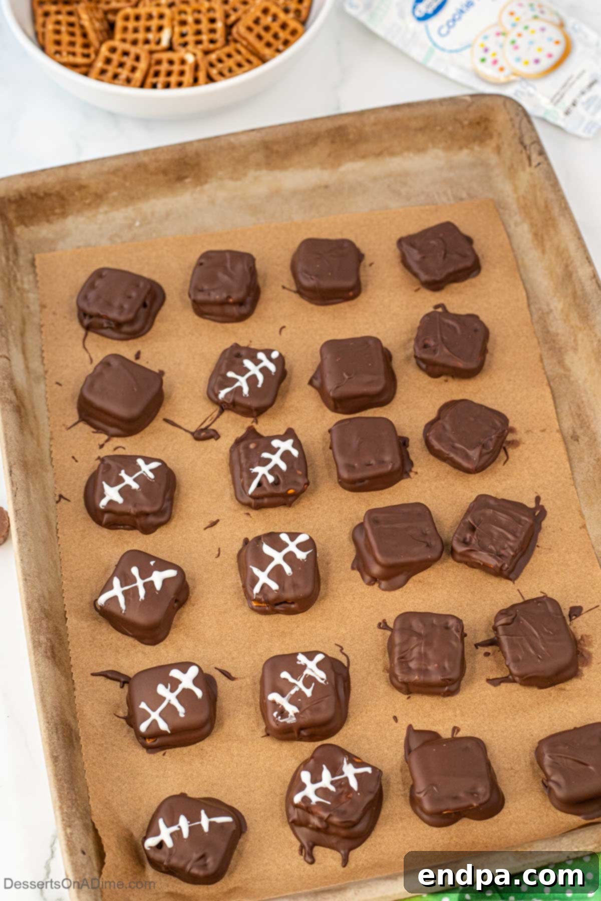 Chocolate covered pretzels cooling on a baking sheet lined with parchment paper.