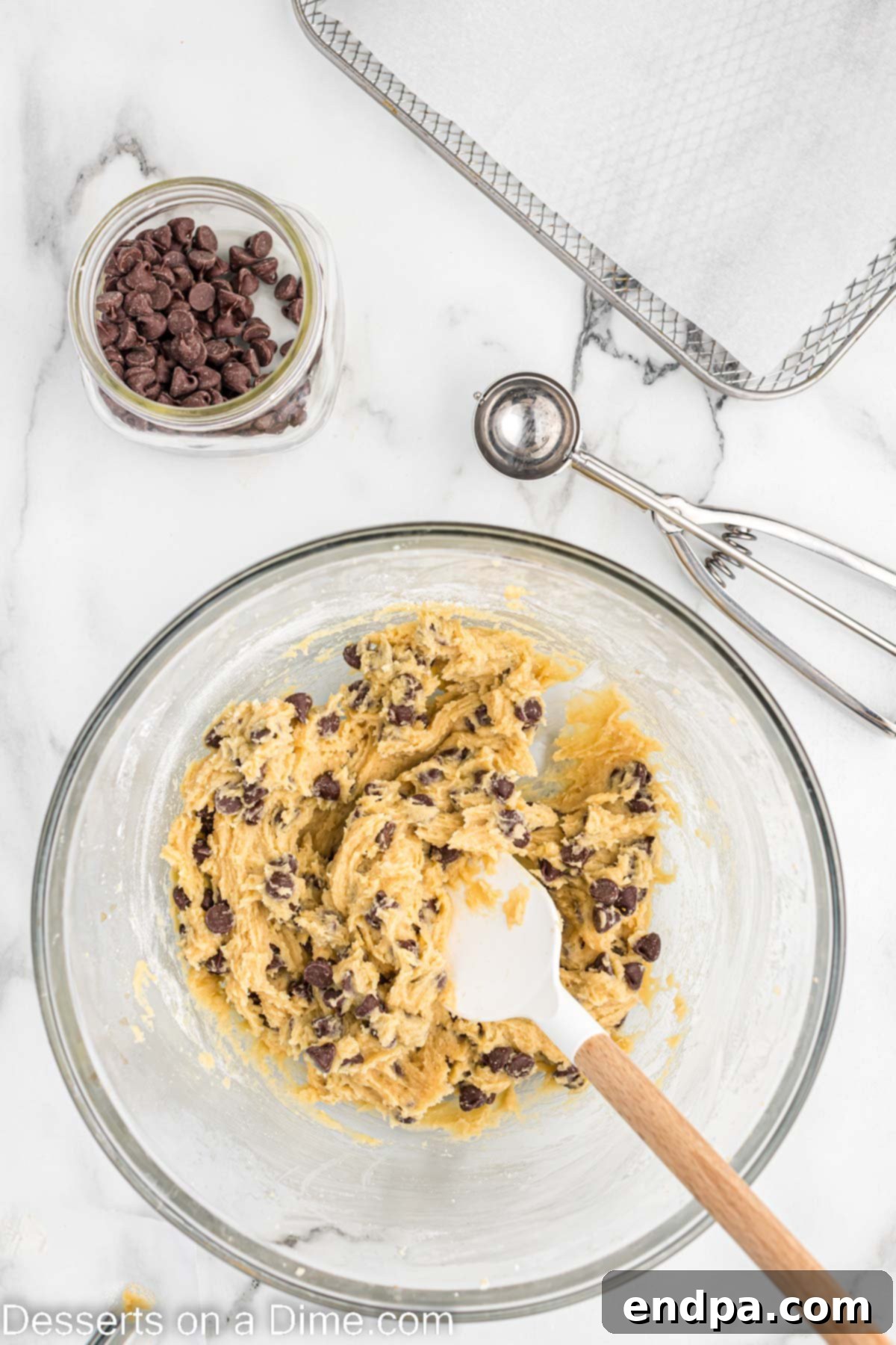 A close-up shot of chocolate chips gently folded into the cookie dough in a mixing bowl.