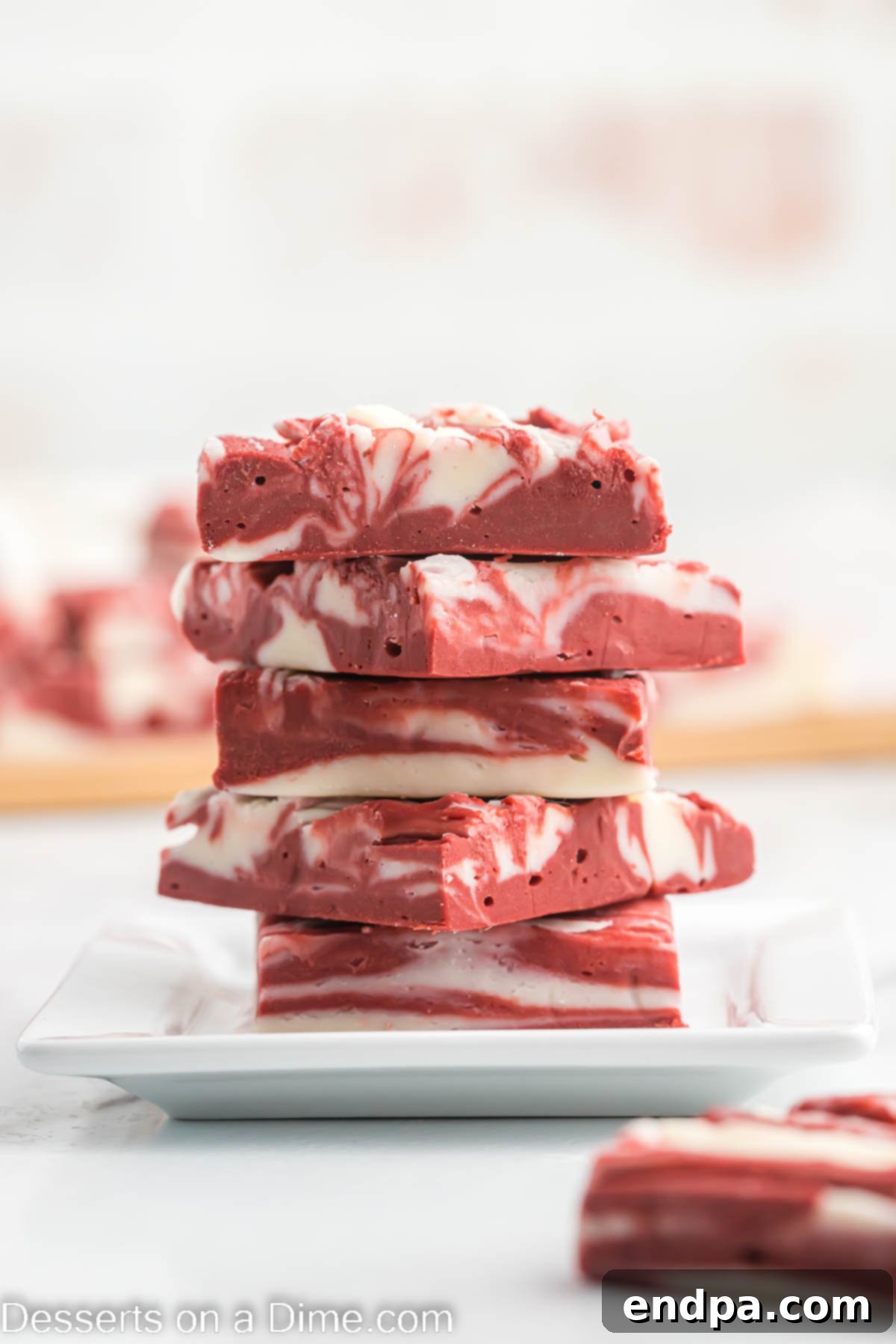Decadent red velvet fudge squares artfully stacked, showcasing their beautiful swirled pattern.