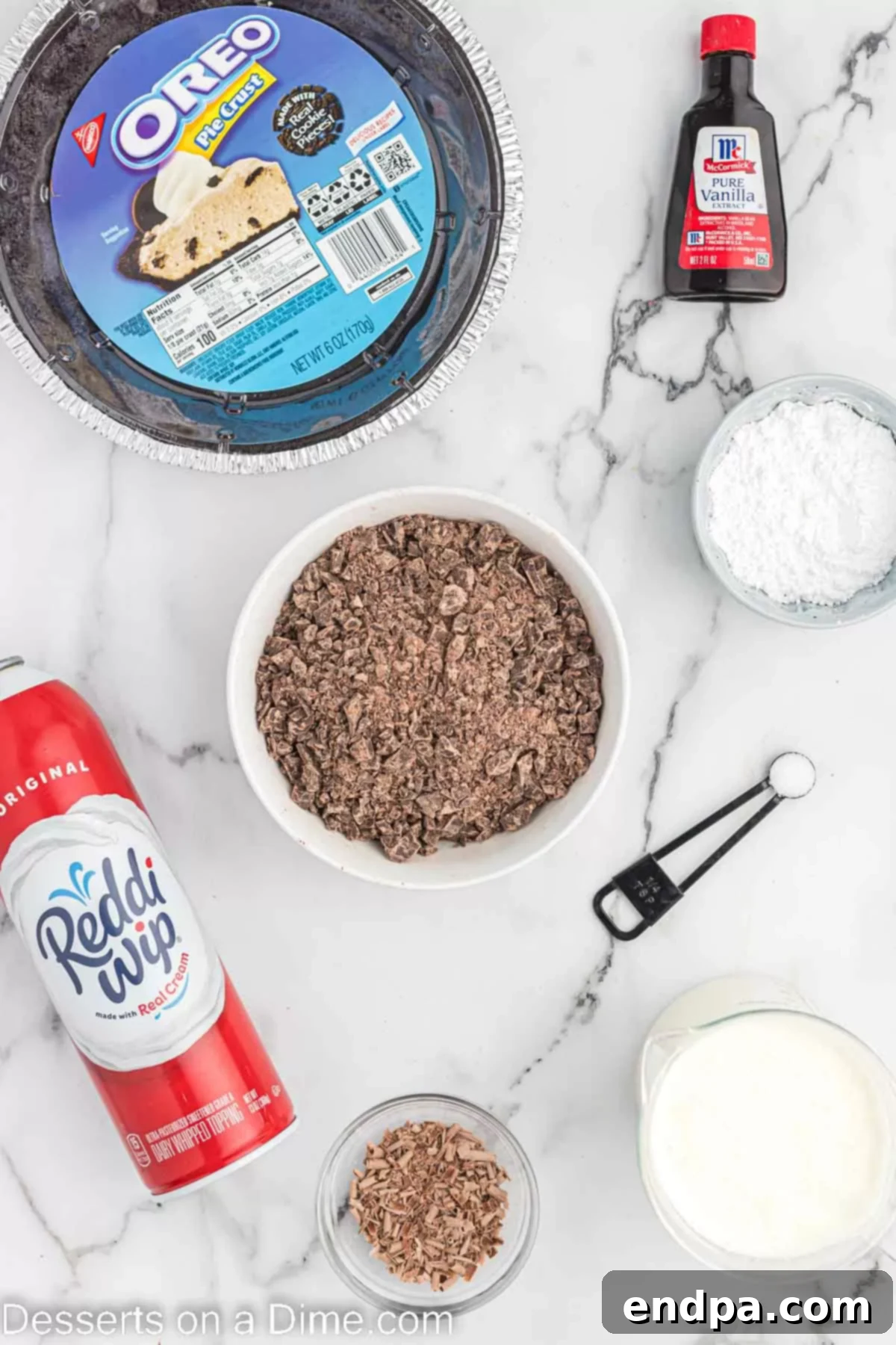 Decadent Chocolate Mousse Delight 3 Ingredients laid out for Chocolate mousse pie, including an Oreo pie crust, chocolate chips, heavy whipping cream, vanilla extract, powdered sugar, whipped cream, and chocolate shavings.