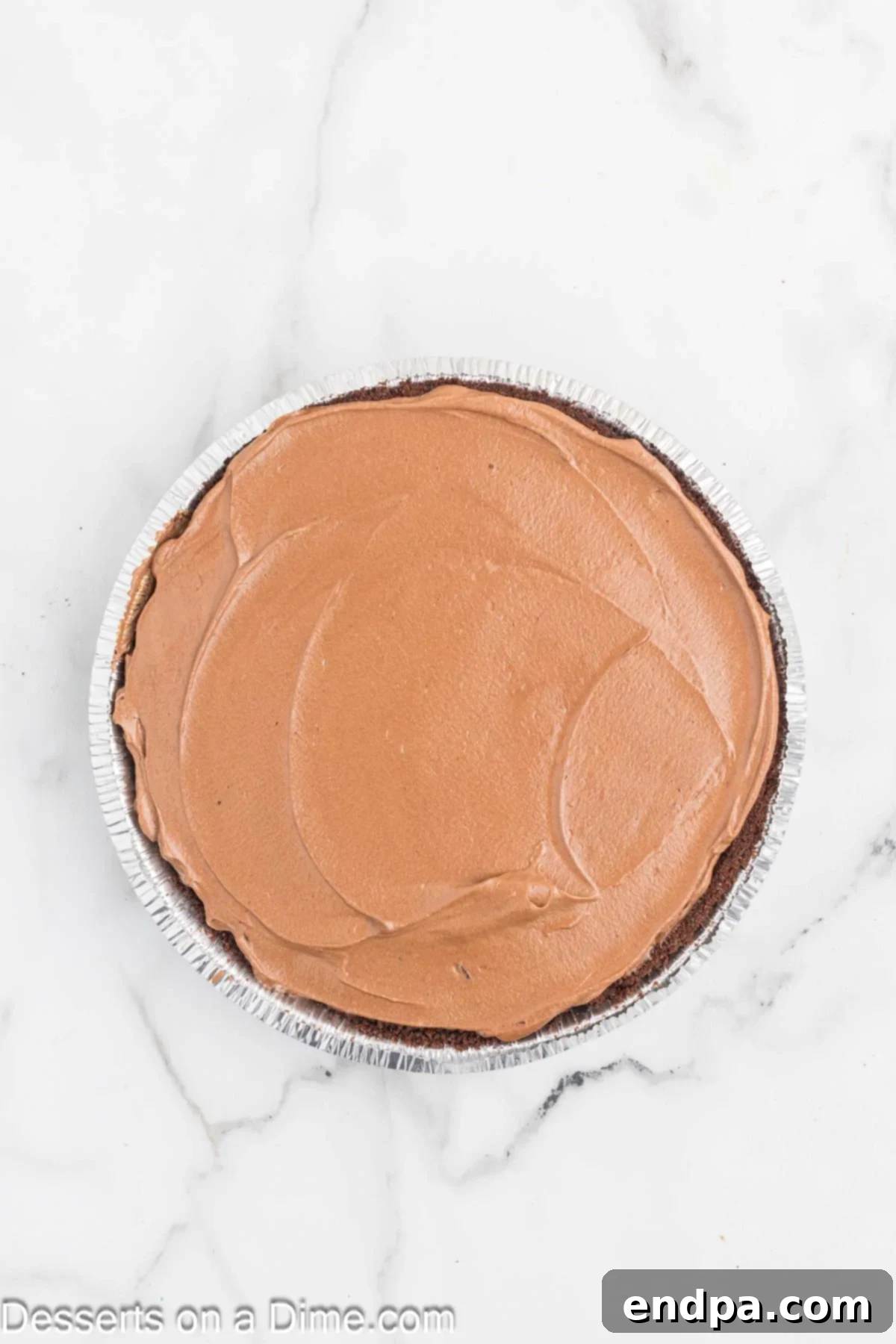 Decadent Chocolate Mousse Delight 6 Chocolate mousse mixture being spread evenly into an Oreo pie crust.