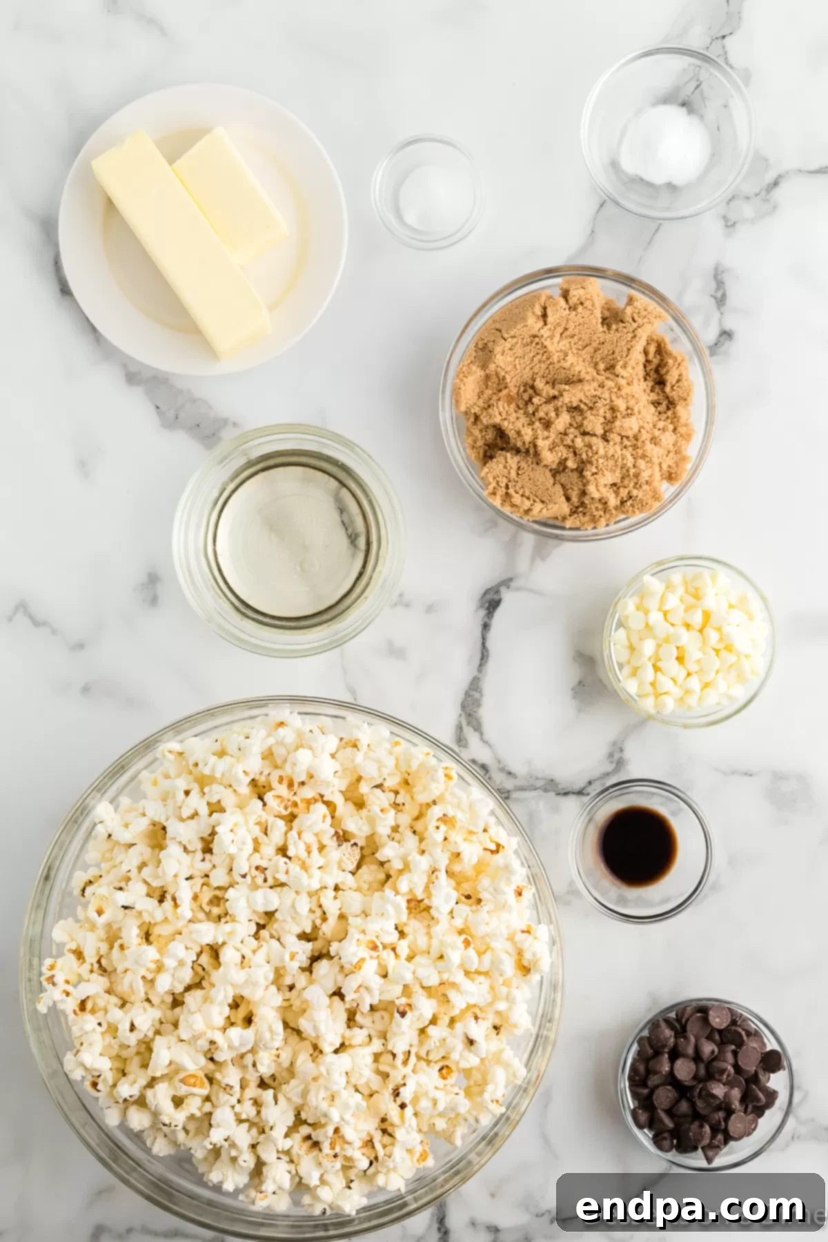 Ingredients for Zebra popcorn - popcorn, brown sugar, butter, corn syrup, baking soda, vanilla, white chocolate chips, dark chocolate chips laid out on a surface.