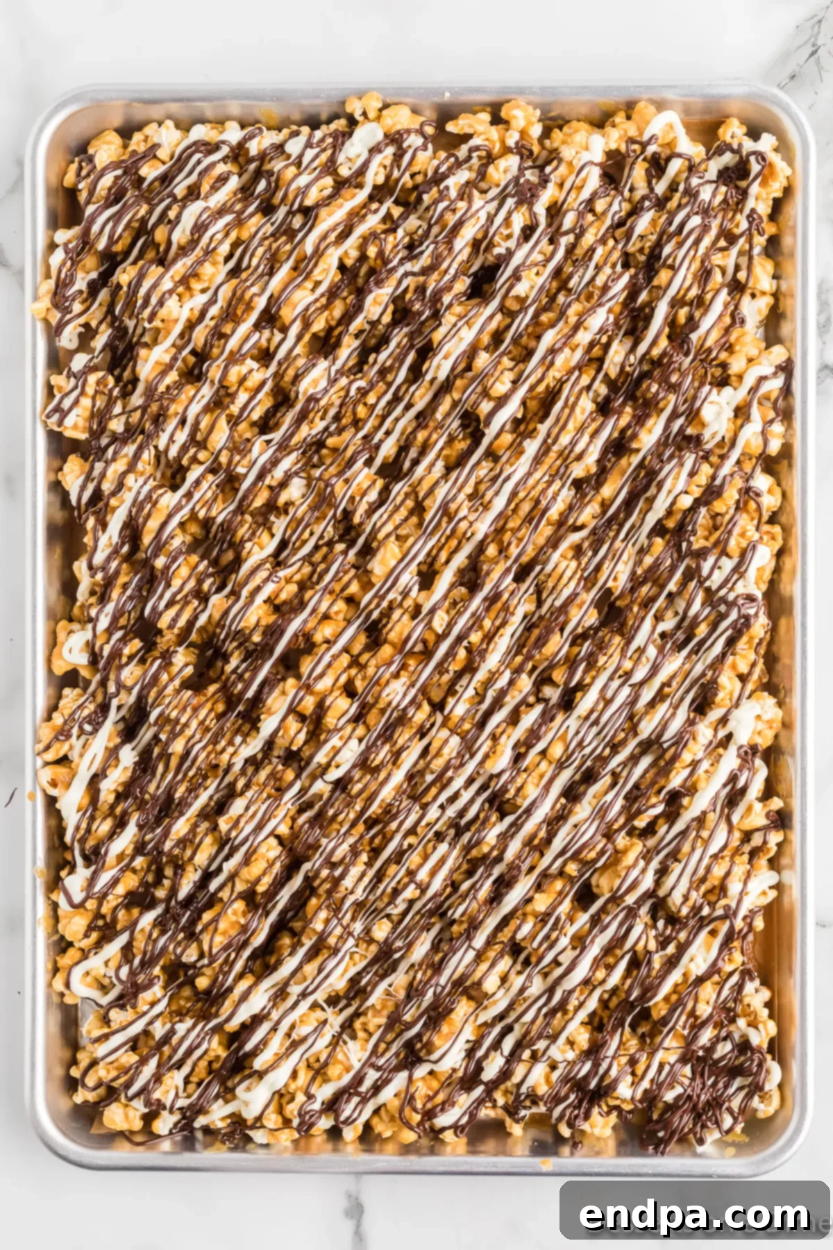 Caramel popcorn topped with both white and dark chocolate drizzles, creating the zebra pattern. 