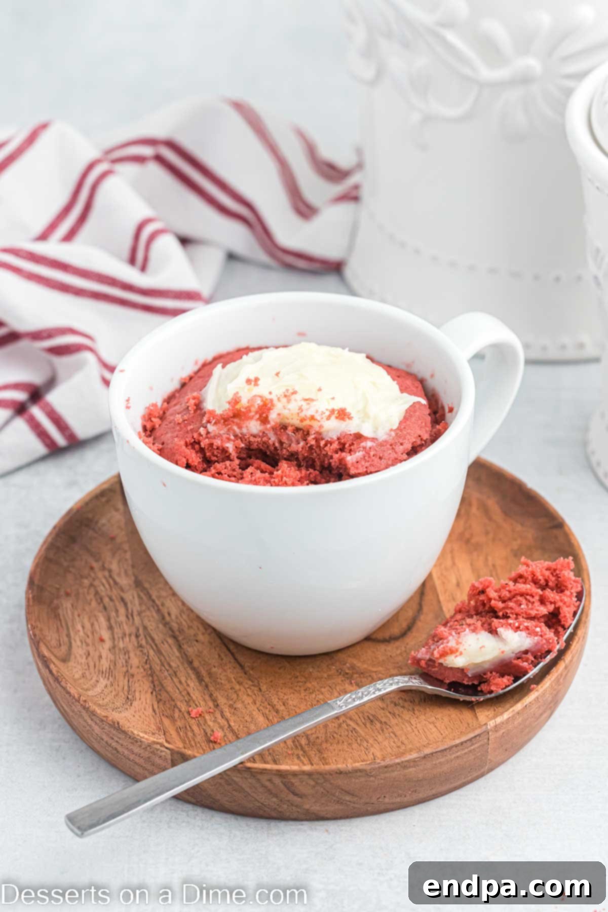 Red Velvet Mug Cake topped with cream cheese frosting with a bite on a spoon, showcasing its rich red color and creamy texture