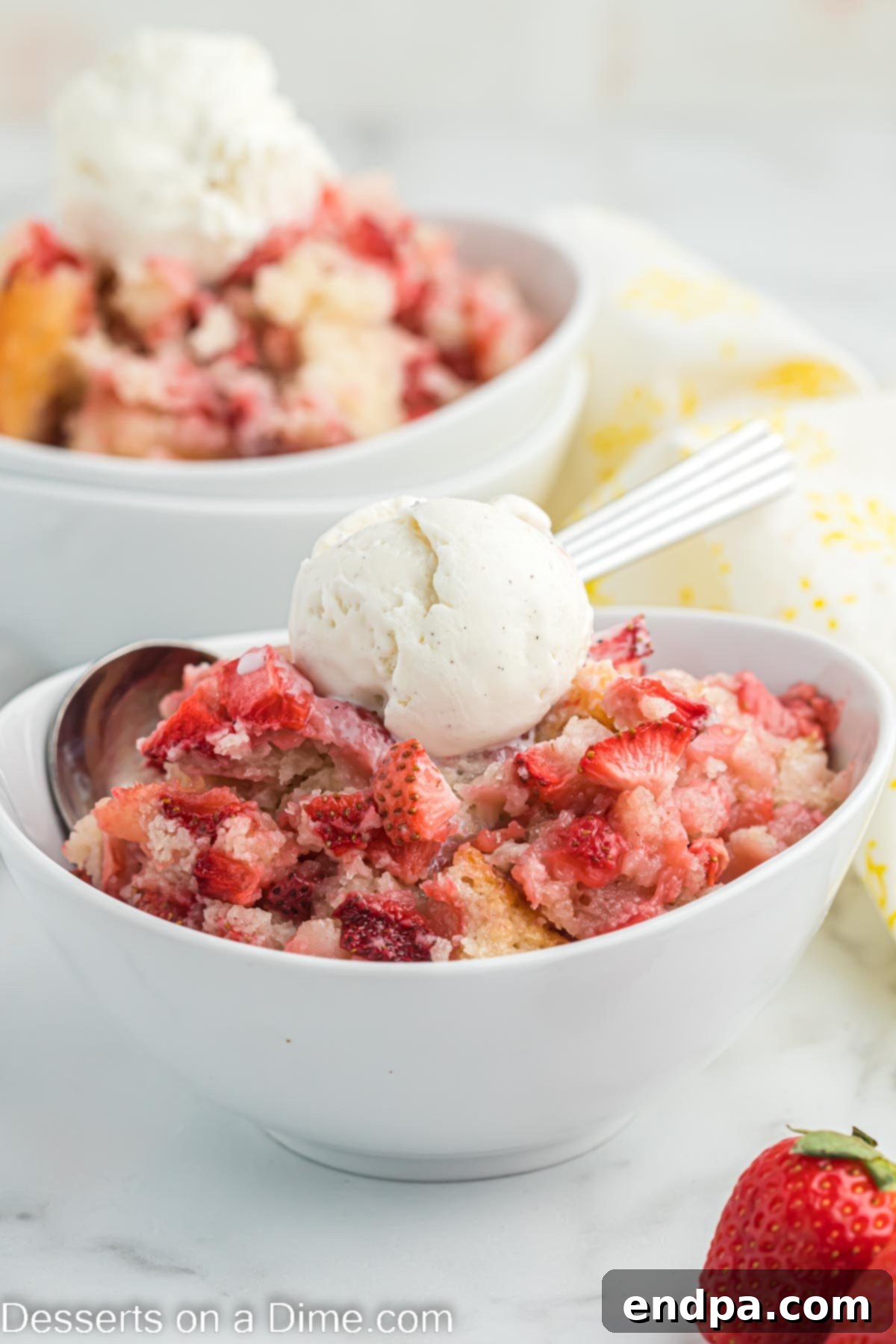 Strawberry cobbler in a bowl topped with ice cream. 