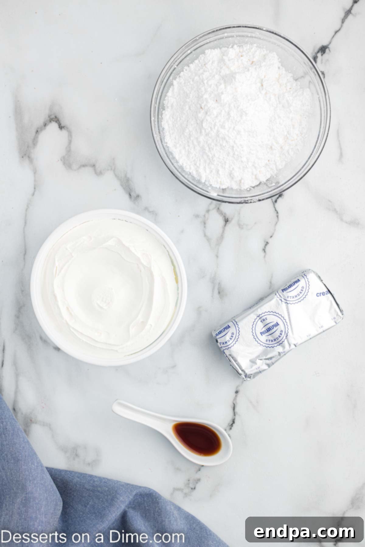 Ingredients for Cool whip cream cheese frosting - whipped topping, cream cheese, powdered sugar, vanilla extract displayed on a surface.