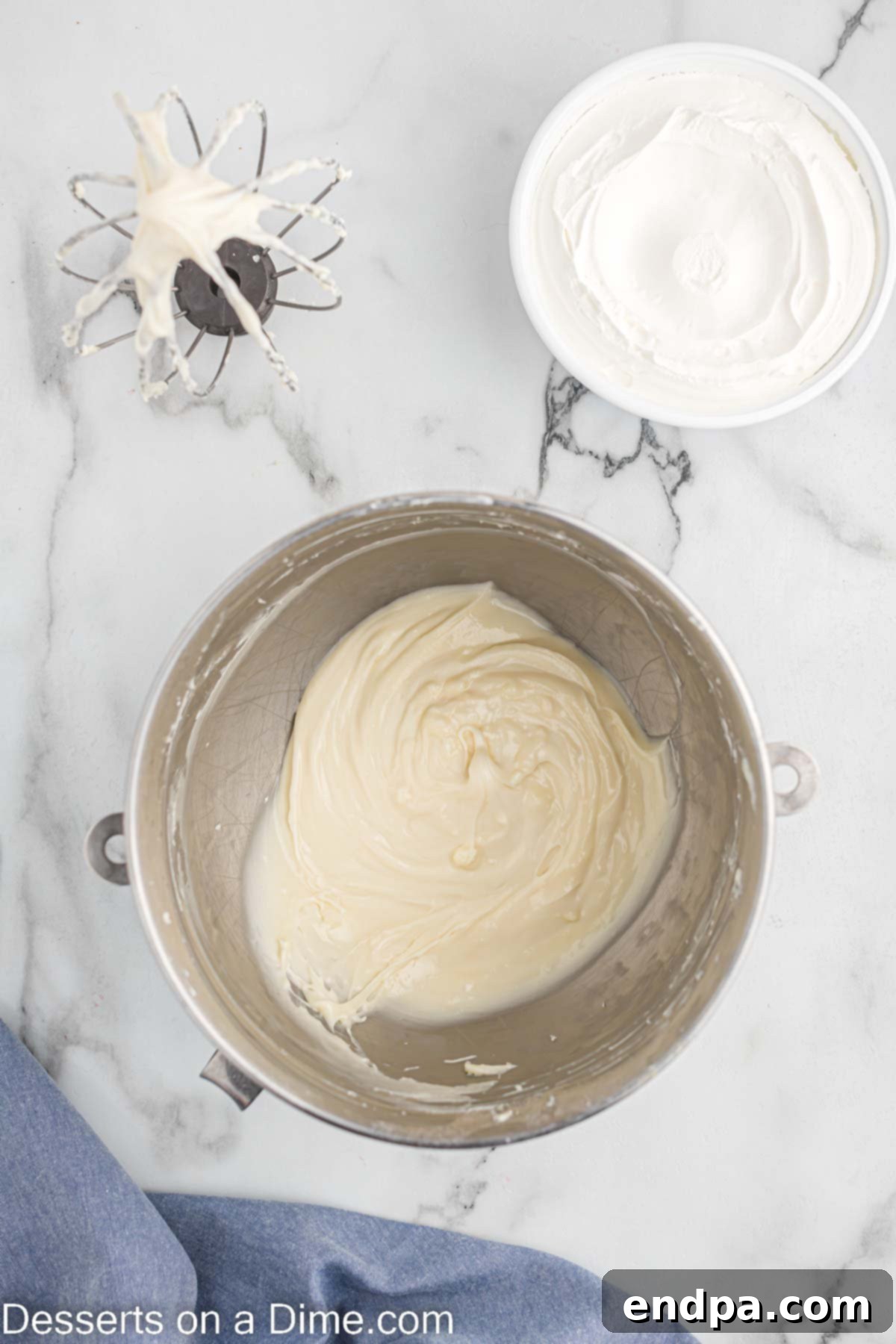Powdered sugar and vanilla extract being added to the beaten cream cheese in a bowl.