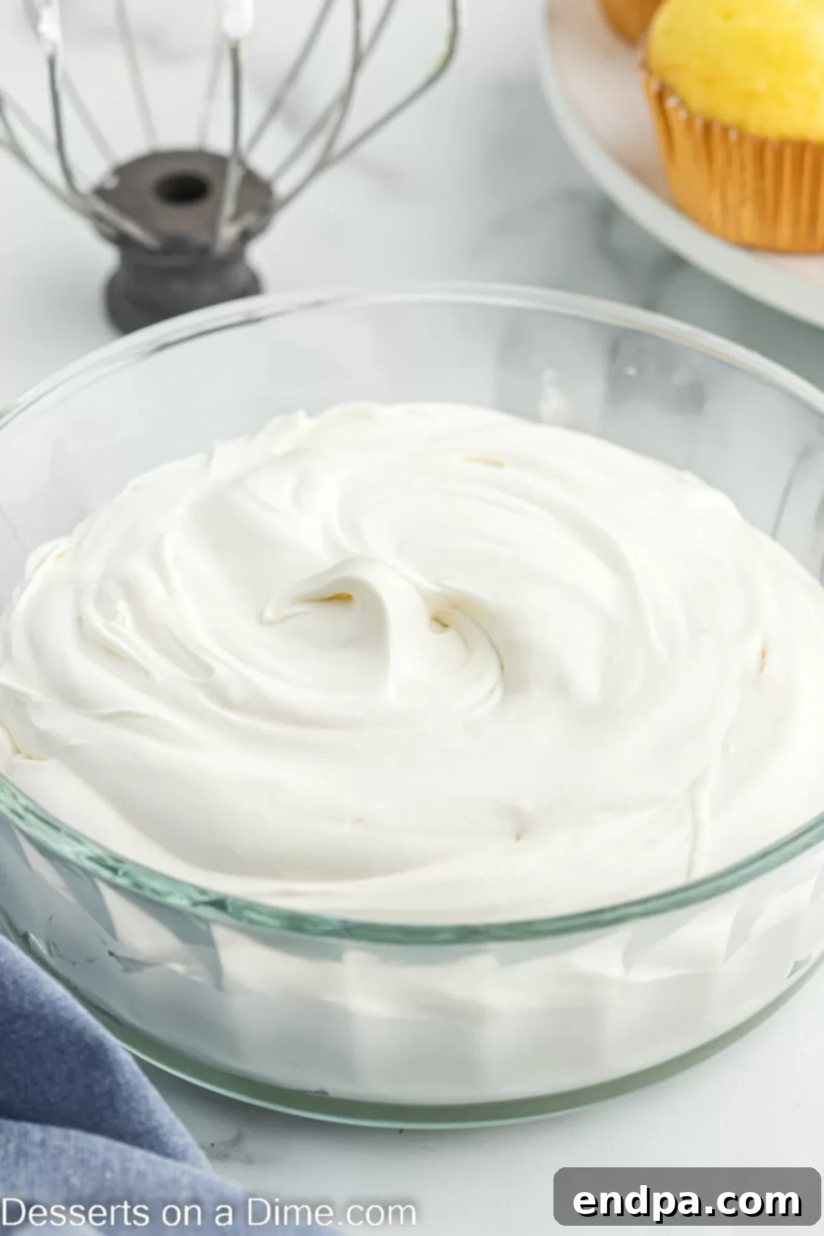 Cool whip cream cheese frosting elegantly swirled in a glass bowl, showcasing its light and airy texture.