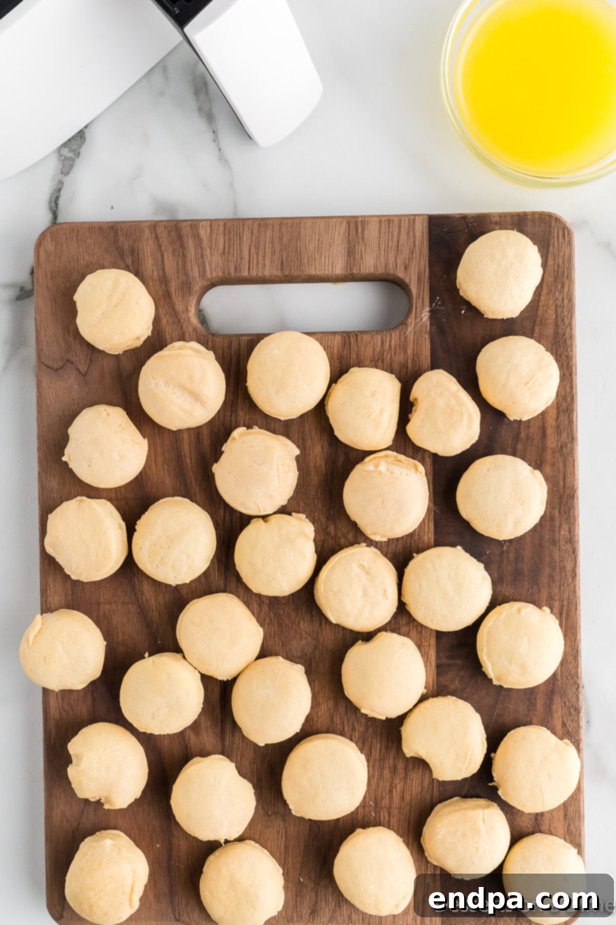 Air Fryer Donut Poppers 4 Biscuit dough being cut into small round pieces on a cutting board.