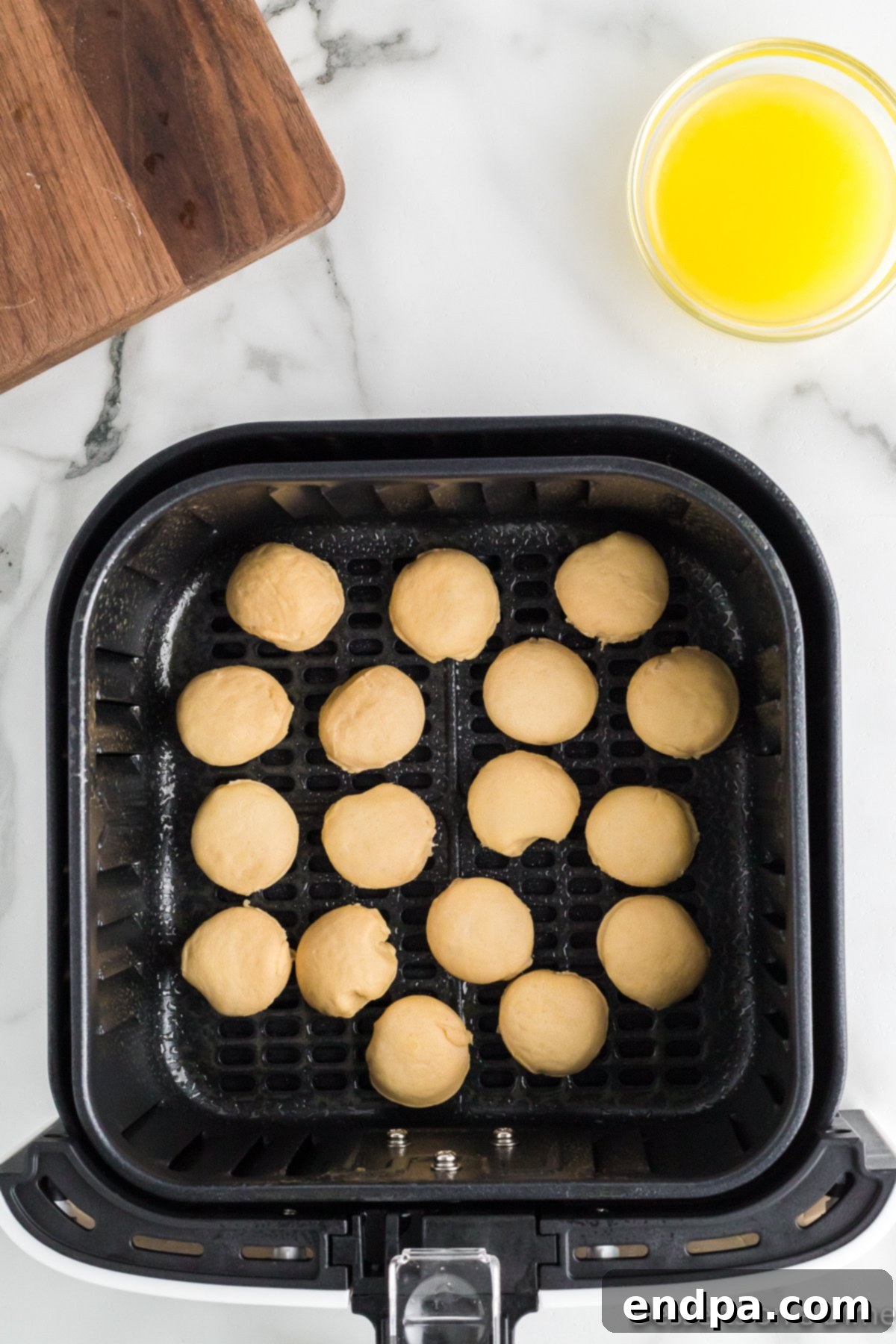 Air Fryer Donut Poppers 5 Small biscuit donut holes arranged in a single layer in an air fryer basket.