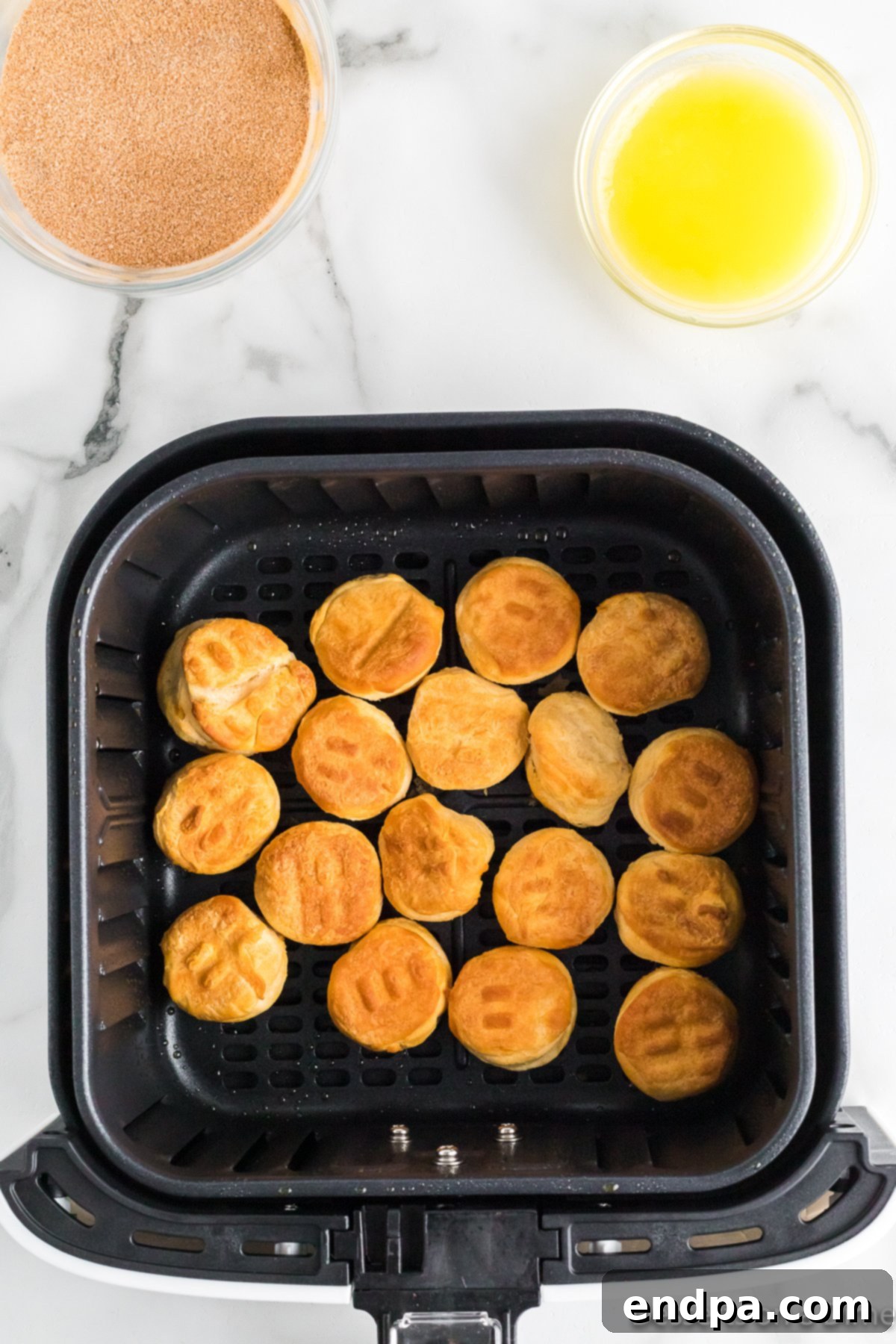 Air Fryer Donut Poppers 6 Cooked, golden brown biscuit donut holes inside the air fryer basket.