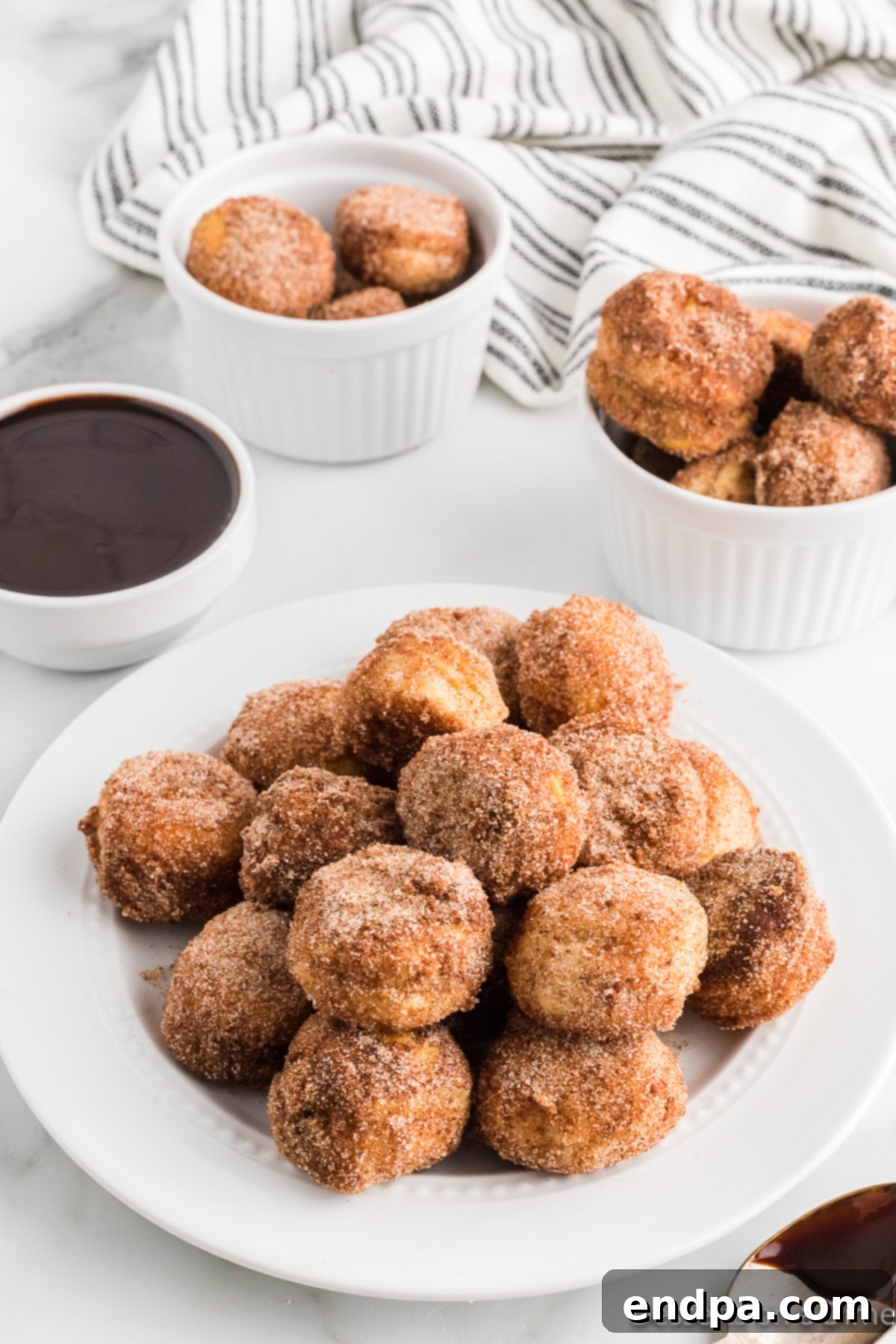 Air Fryer Donut Poppers 10 Air fryer donut holes served on a plate with a dusting of cinnamon sugar.
