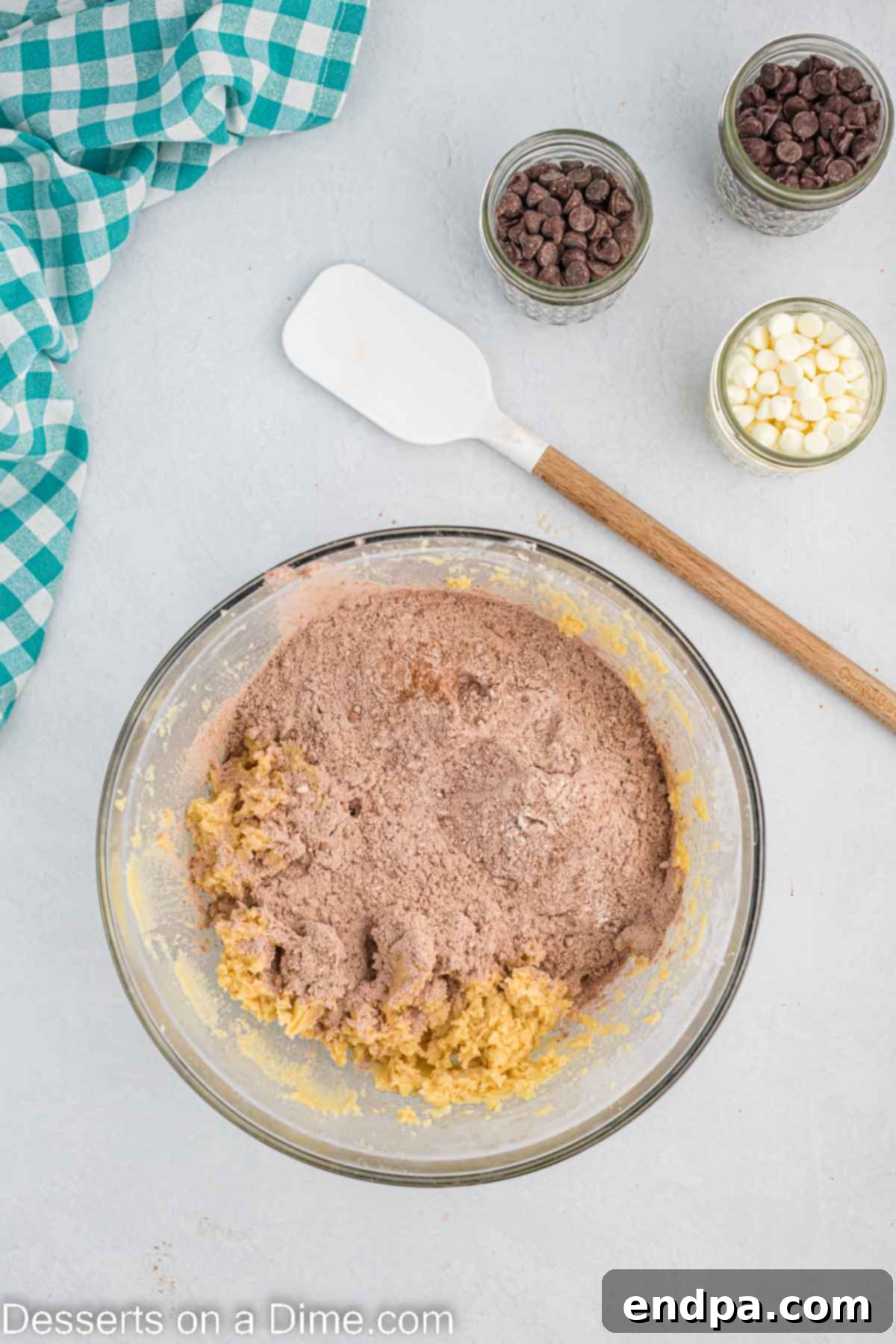 Wet and dry ingredients being combined gently in a large mixing bowl to form cookie dough.