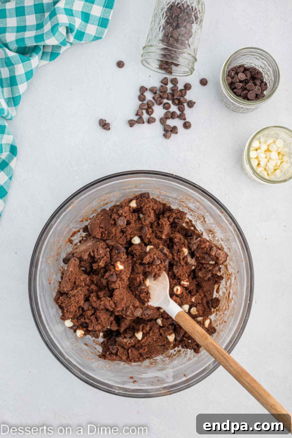 Various chocolate chips being folded into the cookie dough by hand.