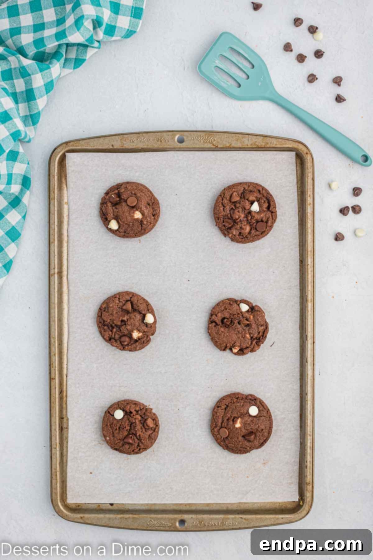 Freshly baked triple chocolate cookies cooling on a baking sheet.