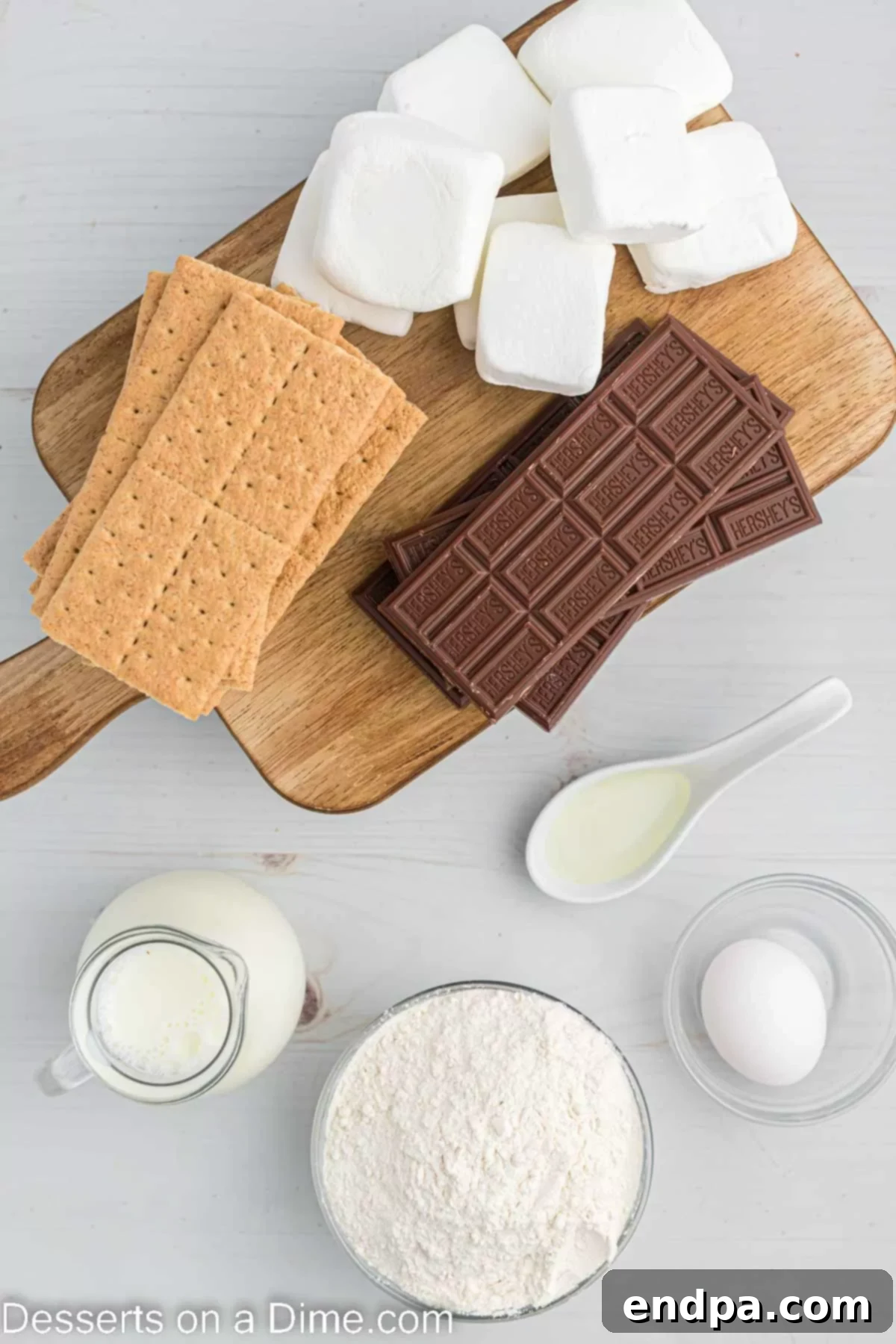 Crispy Golden Smores Delight 3 An array of ingredients for Deep Fried S'mores, including graham crackers, marshmallows, chocolate bars, pancake mix, egg, milk, and oil.