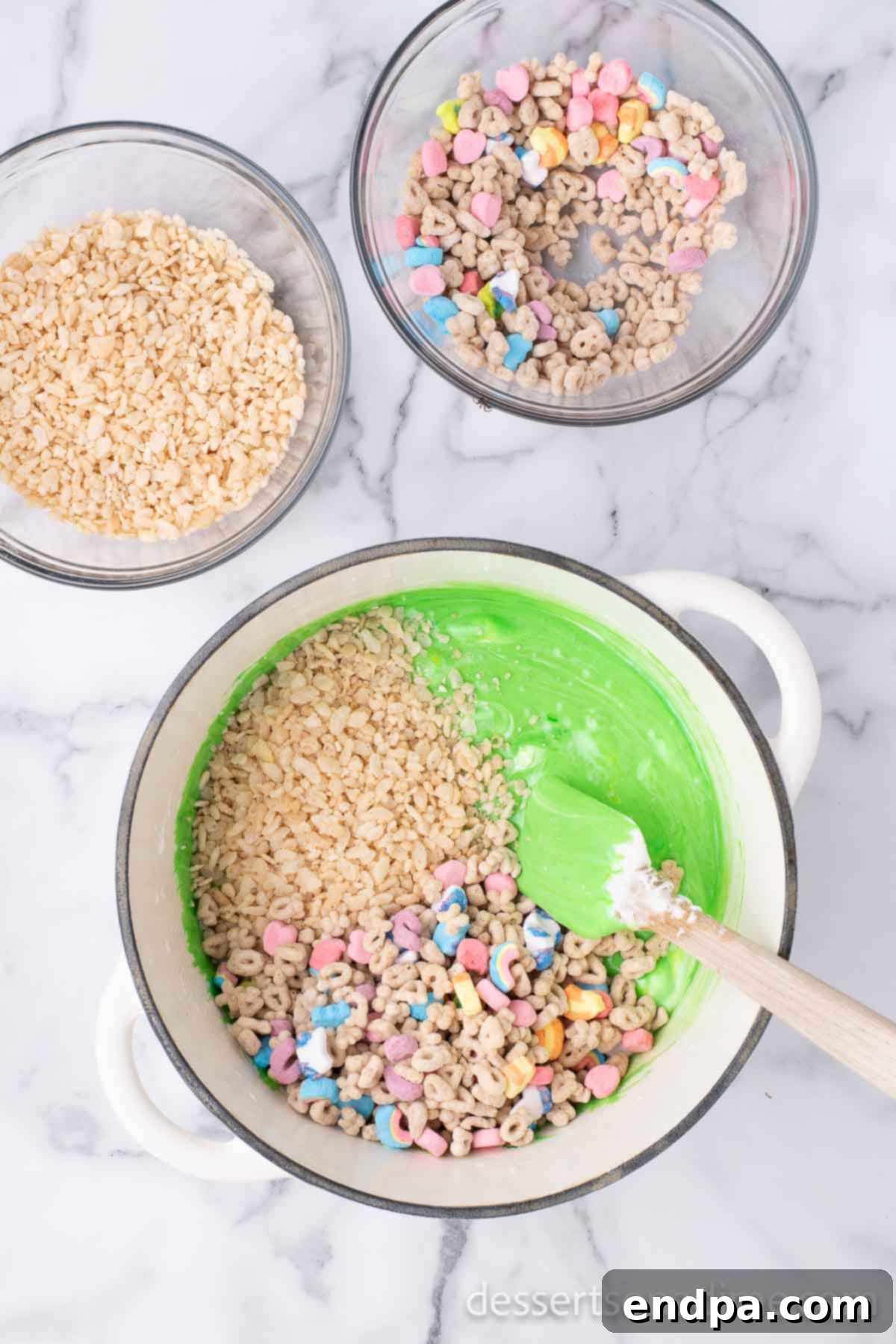 Shamrock Krispie Squares 6 Rice Krispies and Lucky Charms cereal being stirred into the green marshmallow mixture in a pot.