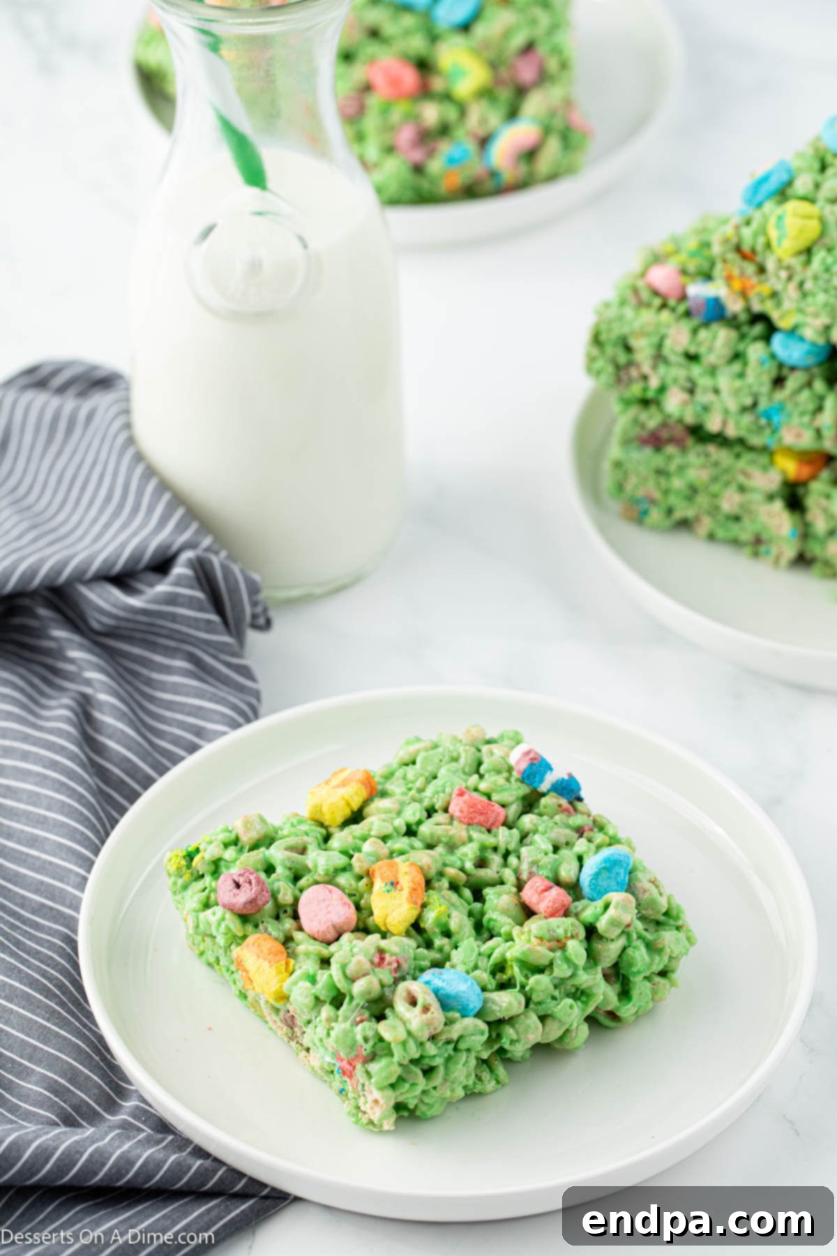Shamrock Krispie Squares 10 A close-up of a stack of St. Patrick's Day Rice Krispie treats, showing the green color and Lucky Charms marshmallows.