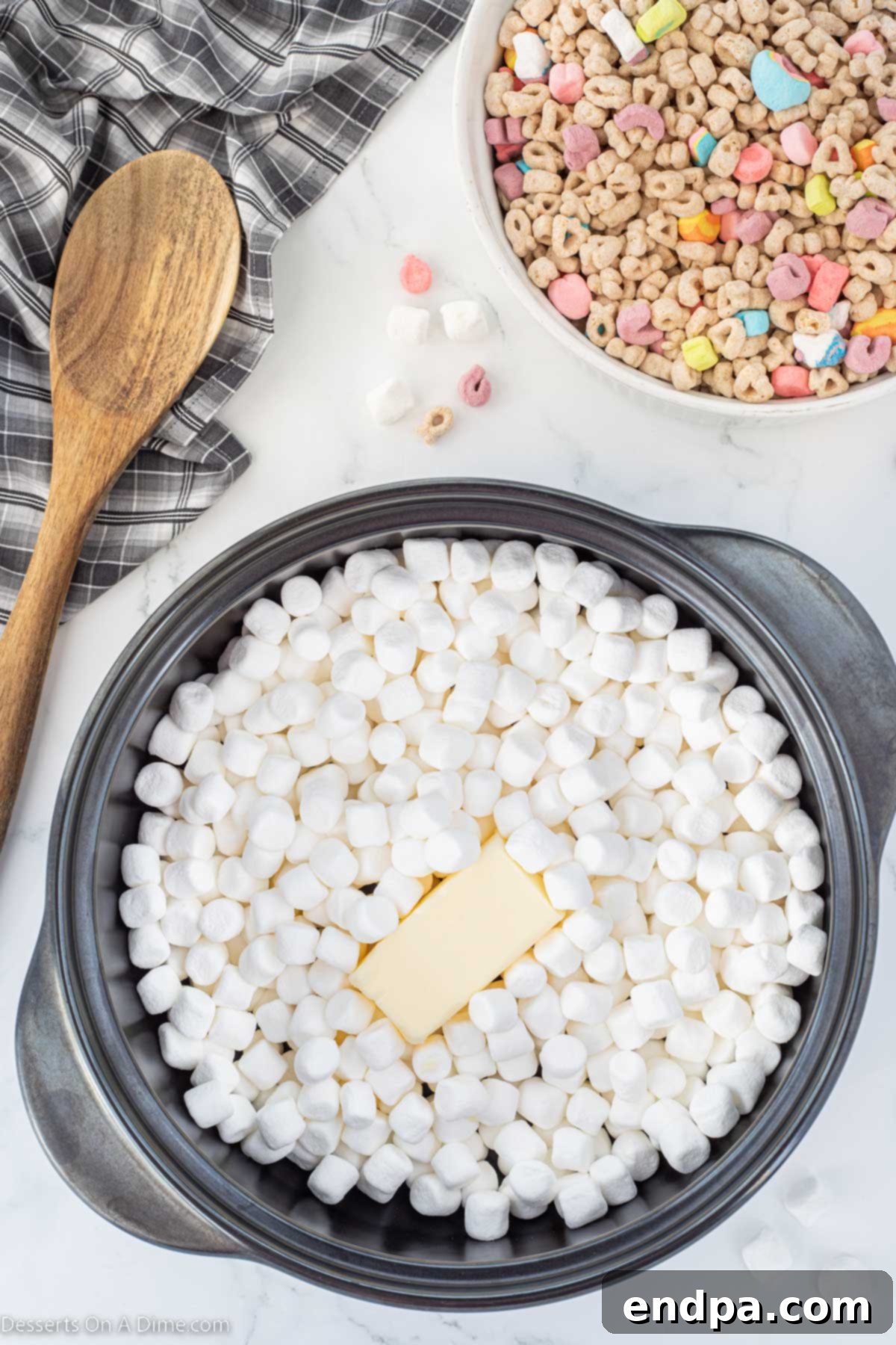 Marshmallows and melted butter combined in a saucepan, being stirred to melt.