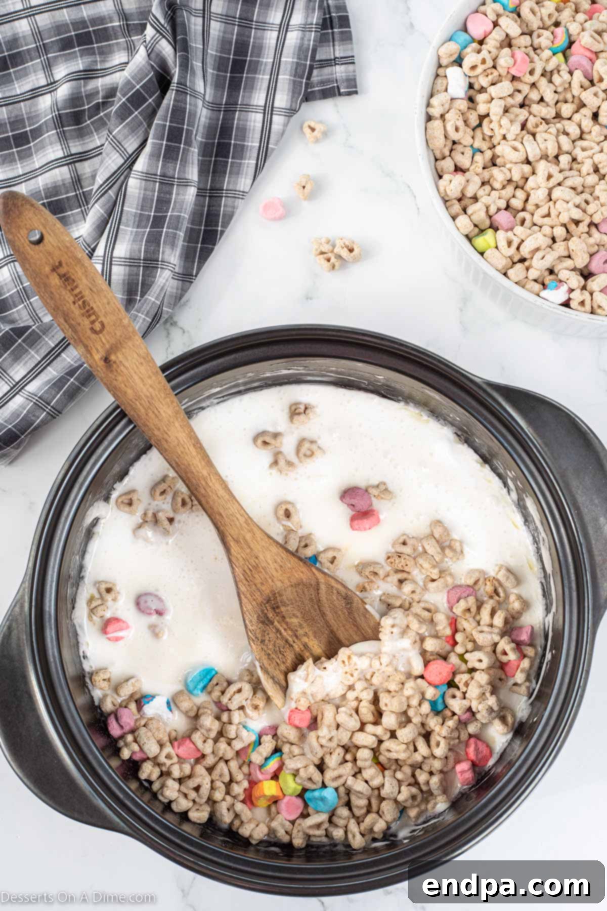 Lucky Charms cereal being stirred into the melted marshmallow and butter mixture in a large pot.